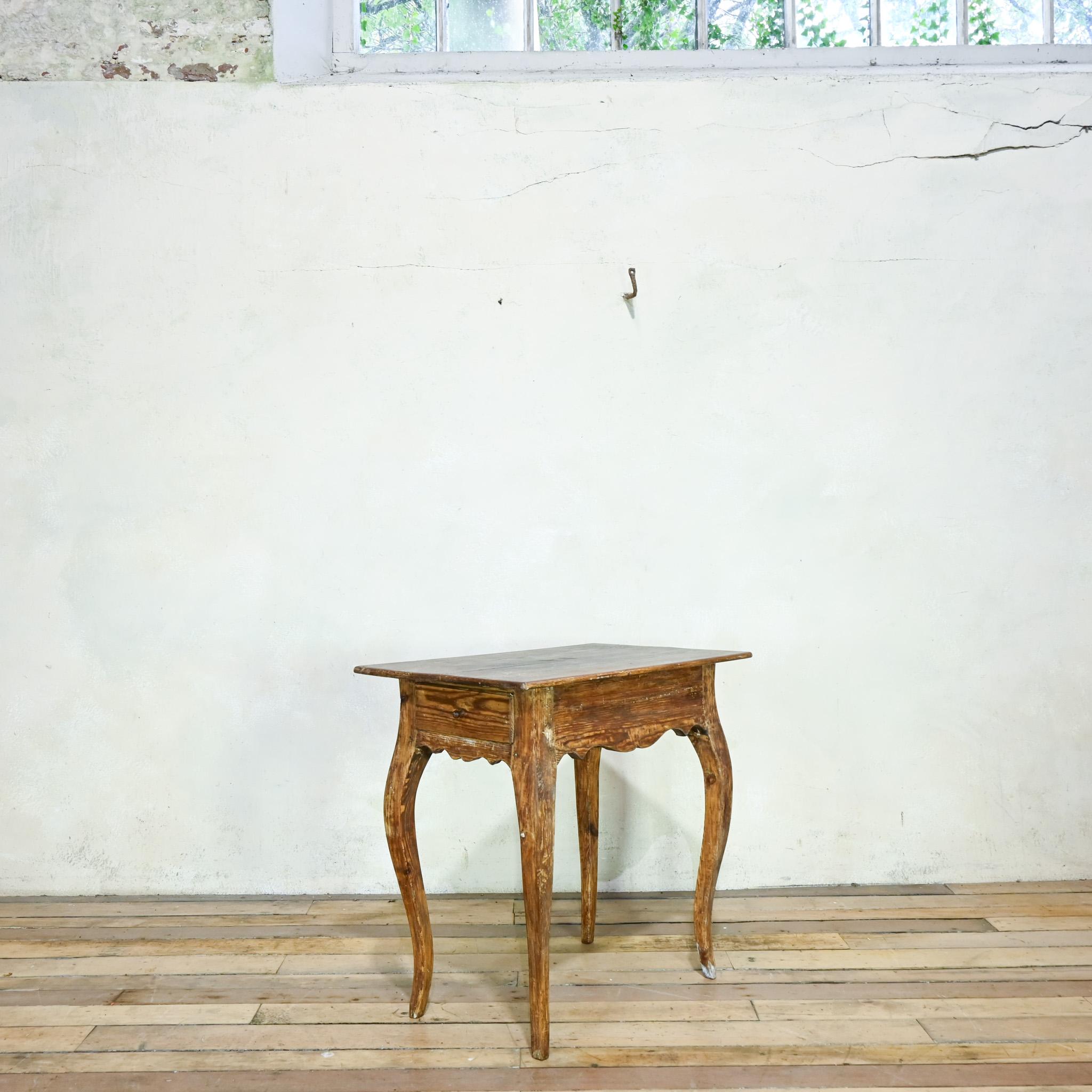 An 18th-century Swedish Rococo table features elegantly curved, outswept legs typical of the furniture of this era. Crafted from pine, the table displays traces of its original paint, adding character to its surface. The scalloped apron beneath