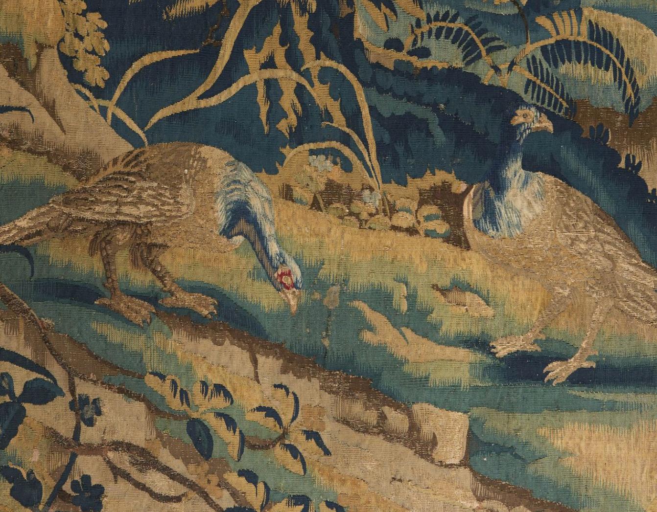 A fine eighteenth century verdure tapestry with lively greenery throughout showing dappled light on the trees, with a pair of pheasants in the foreground, and a clearing in the background, all in perspective and surrounded by lush vegetation. The