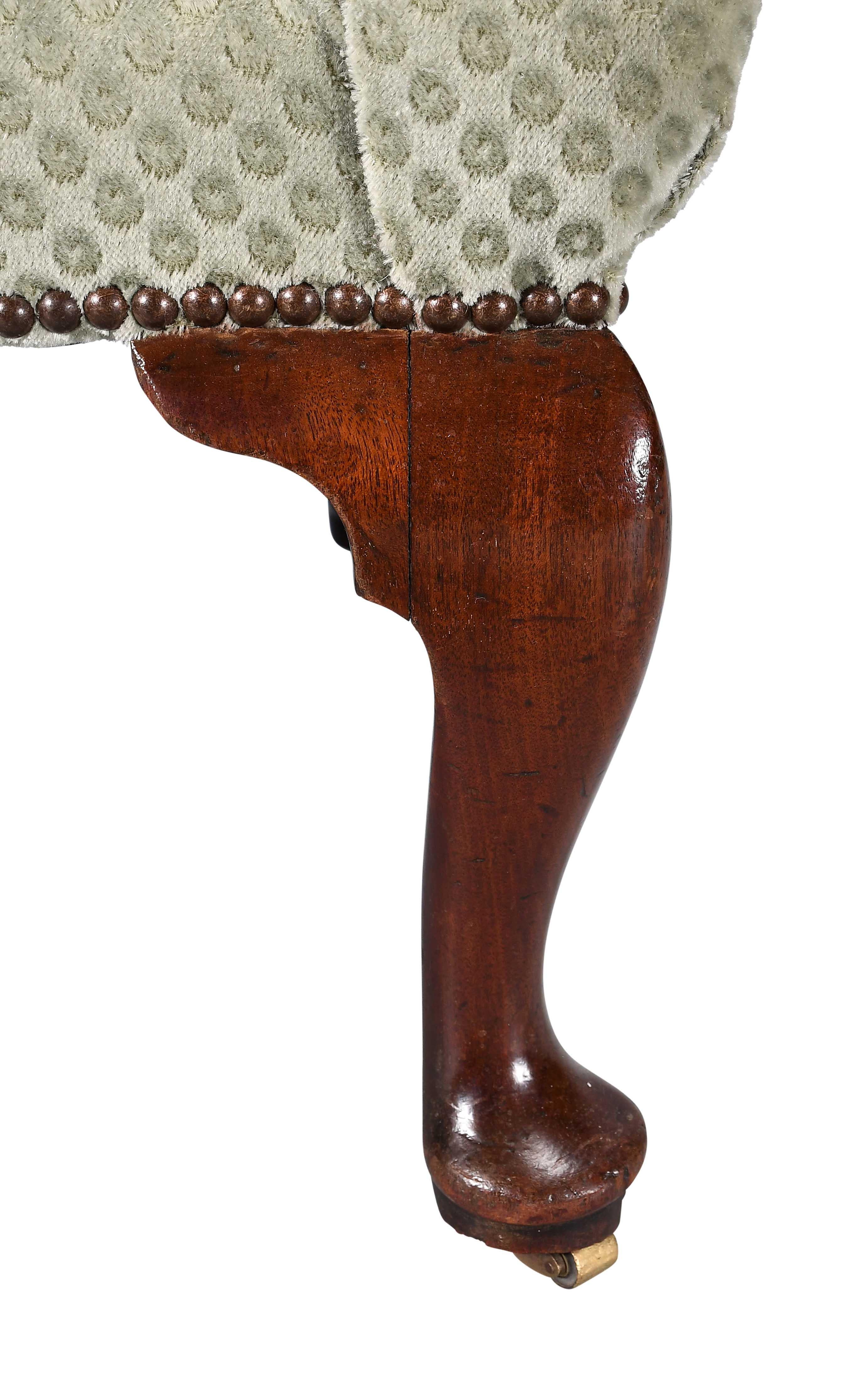 Sillón de orejas de nogal de la época de Jorge II, apoyado sobre cuatro patas cabriolé bien dibujadas, con un espectacular barrido en las patas traseras. Las ruedas de latón están encastradas en los pies almohadillados. Forma encantadora y tamaño