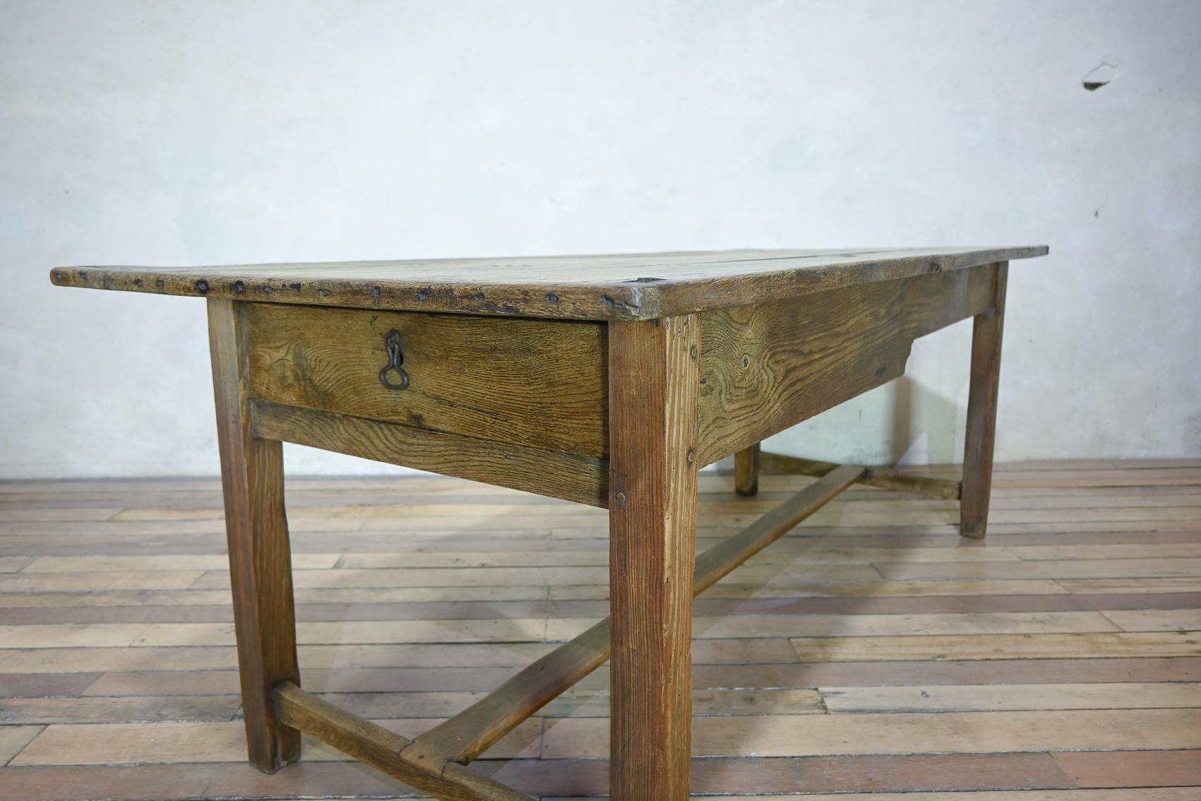 A George III country farmhouse table. Demonstrating a four plank oak cleated top with a frieze drawer to one end of the apron. Raised on pine legs, united by a 'H' shaped Refectory stretcher. Please note the tabletop is removable to manoeuvre around