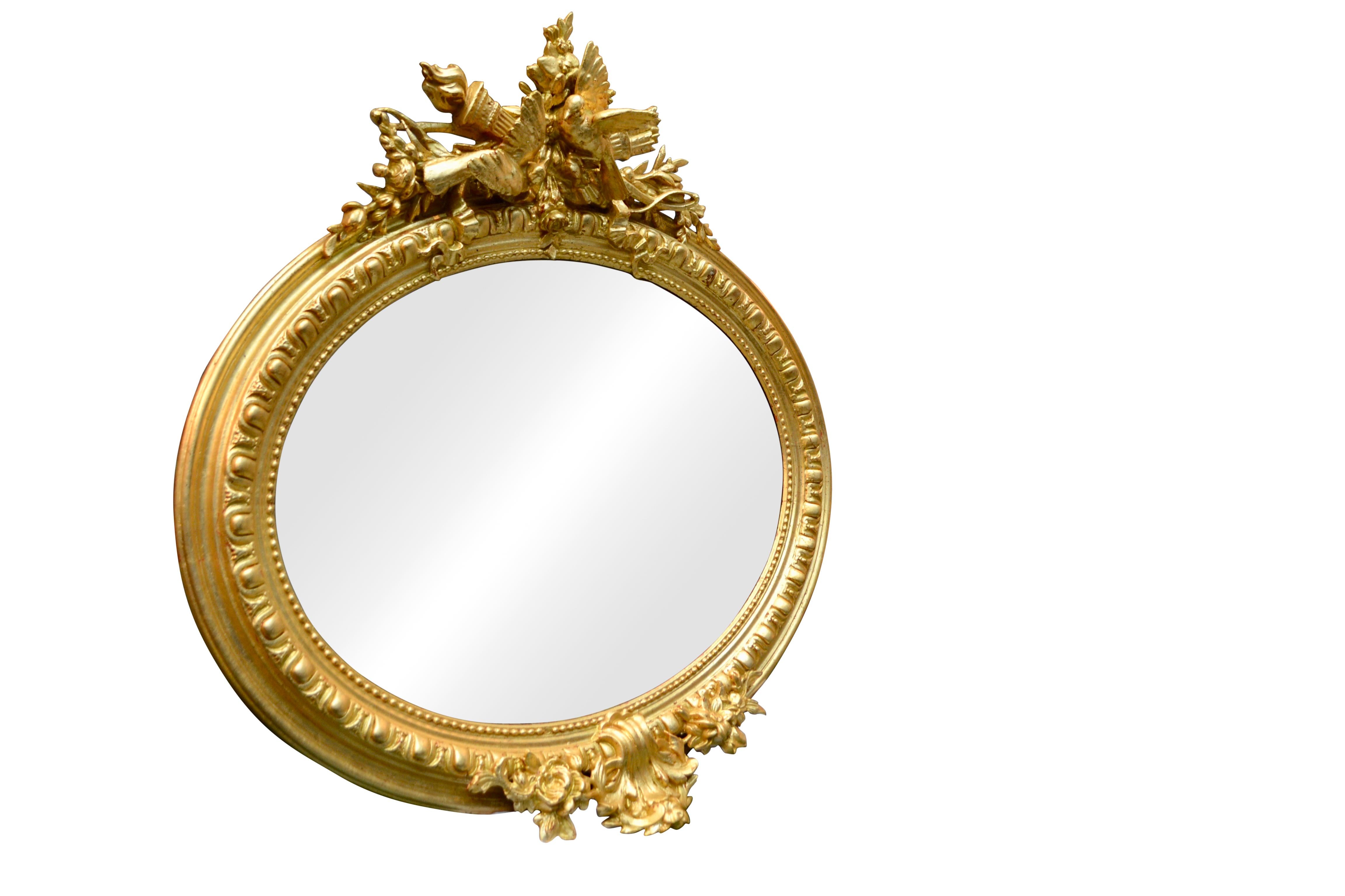 A beautifully carved gilt wood framed oval mirror French, circa 1840, gilt frame carved with an egg and dart design alternating with convex fillets and an inner gilded beaded loop. At the top the frame is decorated by a large cartouche featuring a