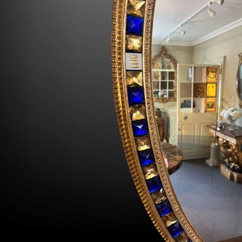 Doré Un site  Miroir mural ovale en bois doré du 19ème siècle avec des bijoux en verre bleu et doré en vente