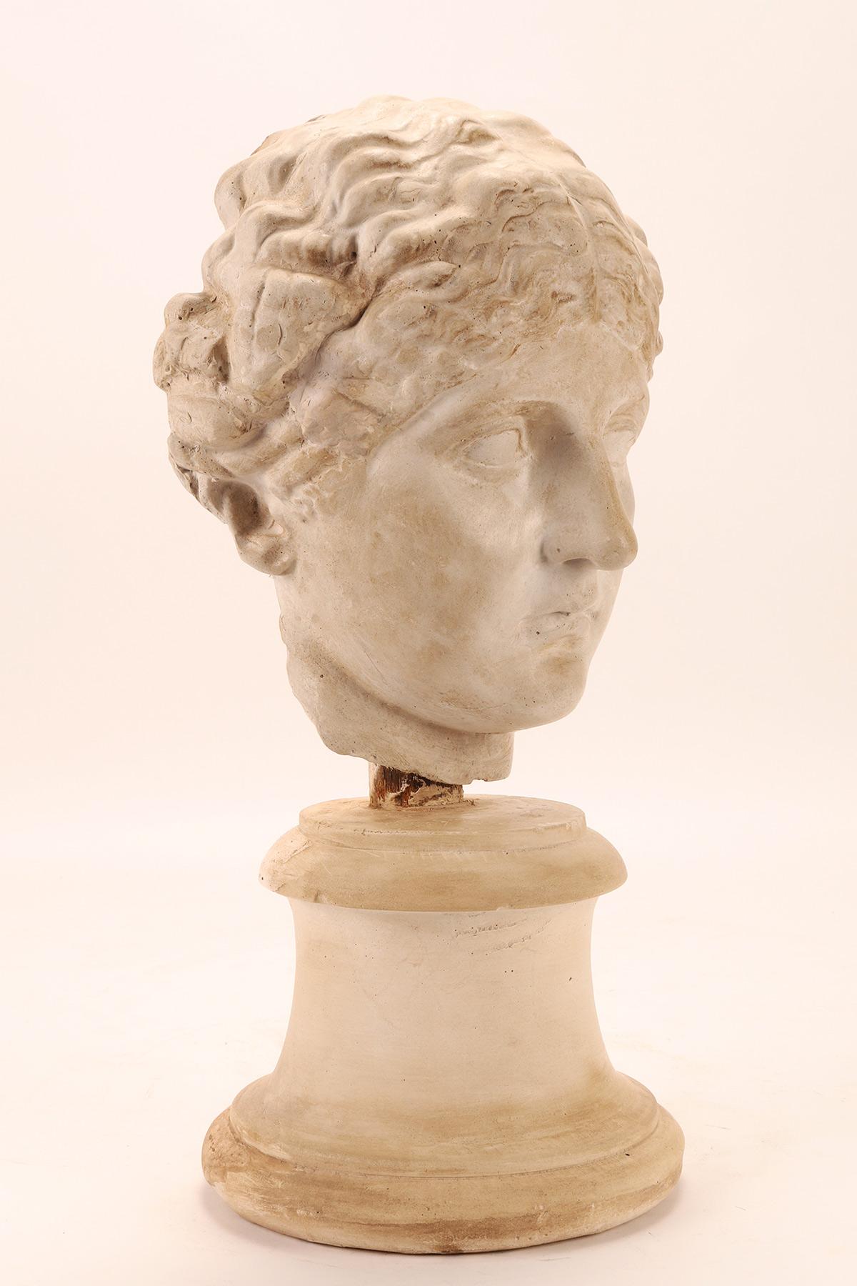 Above the plaster base, by means of a wooden support, the cast of the head of a Roman woman is set. Cast for the teaching drawing in the academy. Italy circa 1890.