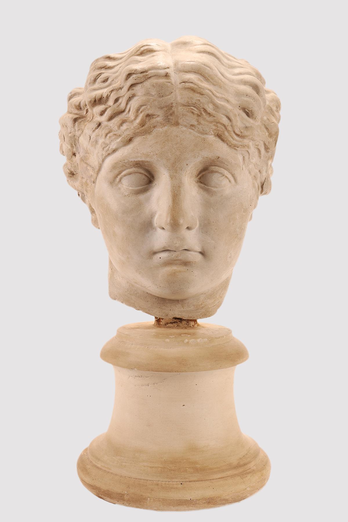 Un cast accademico. Sopra la base in gesso, per mezzo di un supporto in legno, è incastonato il calco della testa di una donna romana. Gettito per l'insegnamento del disegno nell'accademia. Italia circa 1890.