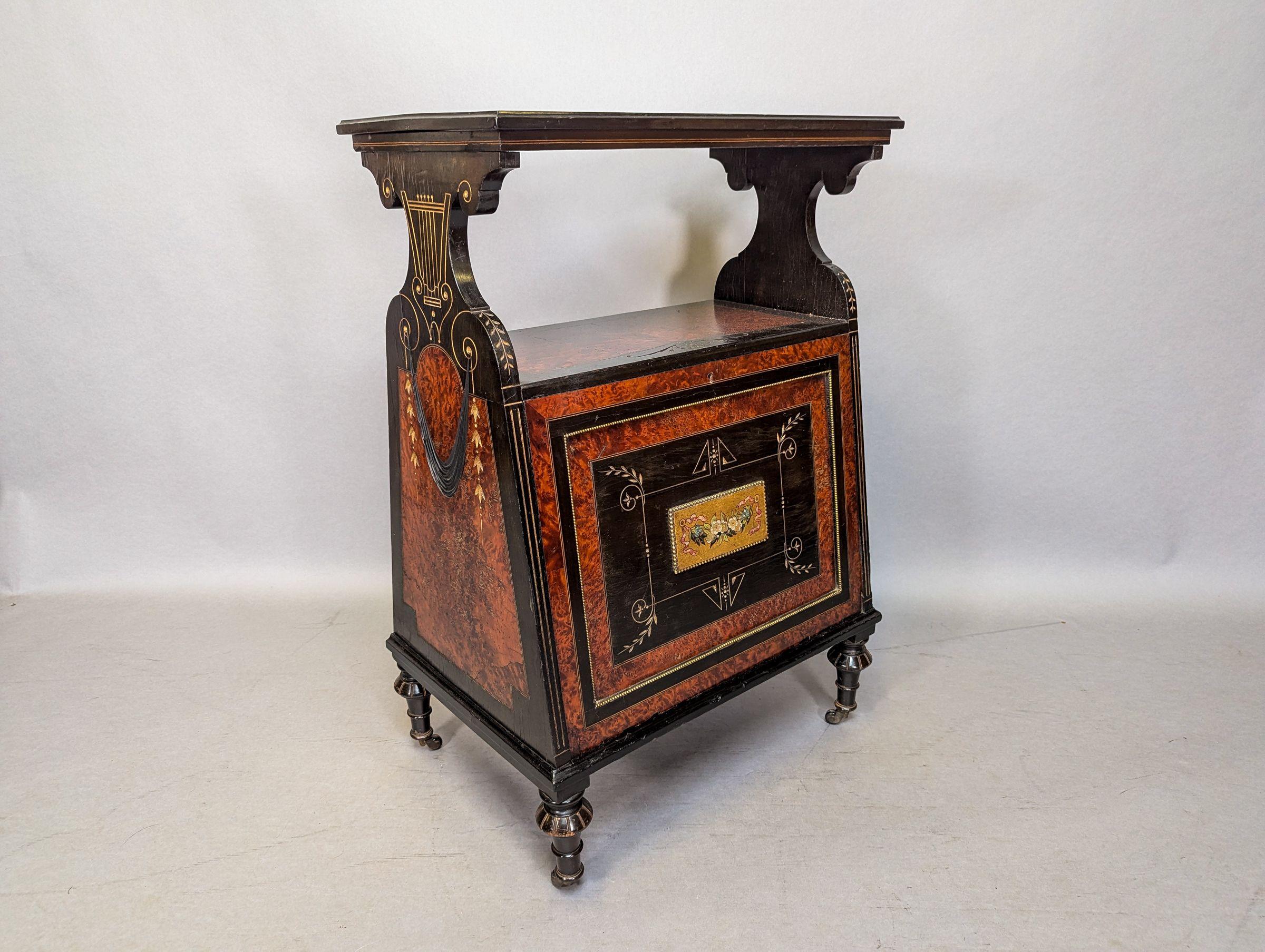 An Aesthetic Movement amboyna and ebonized music cabinet with incised and gilt decoration. The open top with amboyna and incised gilt decoration to the centre is supported by shaped sides with stylized incised gilt harps, and hand-carved ebonized