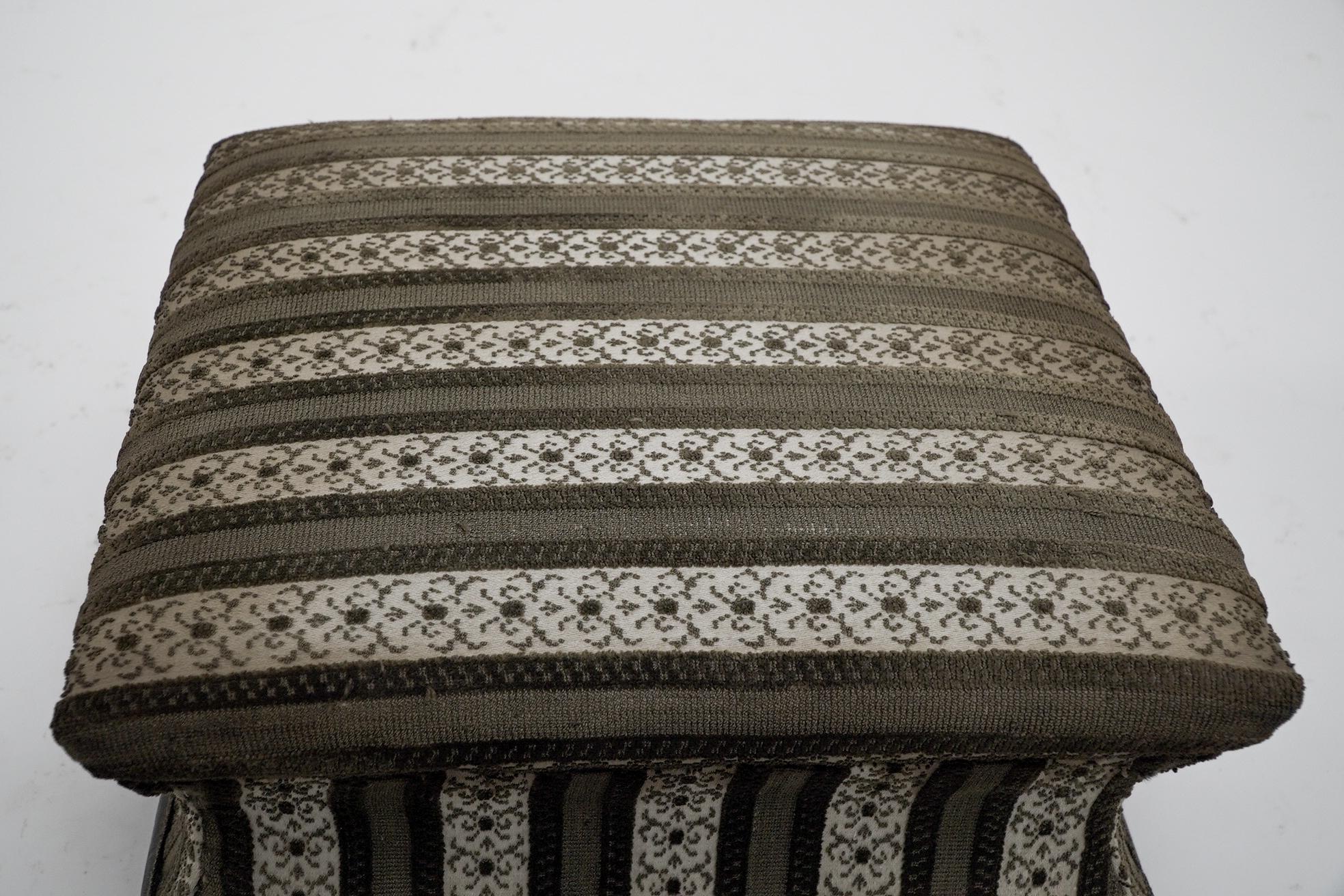 An Aesthetic Movement ebonized footstool with concave-shaped sides and incised parcel gilt decoration on little flat feet with striped braided upholstery.

