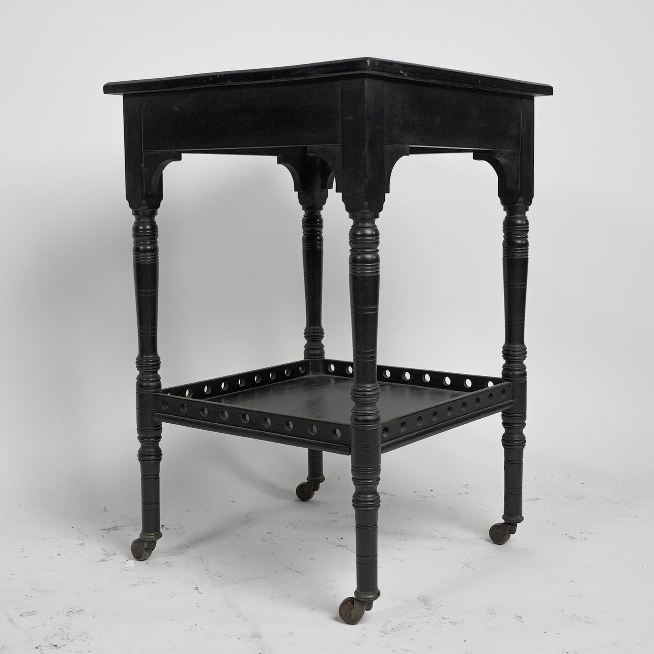 An Aesthetic Movement Walnut ebonized two-tier side table with turned legs,  the lower shelf with raised pierced circular details. 