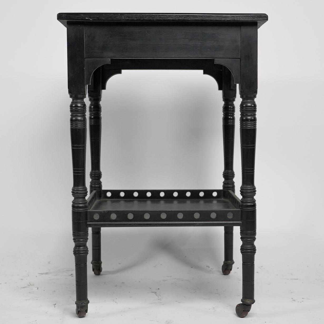 Ebonized An Aesthetic Movement ebonized walnut two tier side table with a pierced gallery For Sale