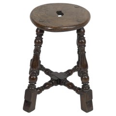 Antique An Aesthetic Movement Elm stool with a 'S' handle, and a wild grain to the seat.