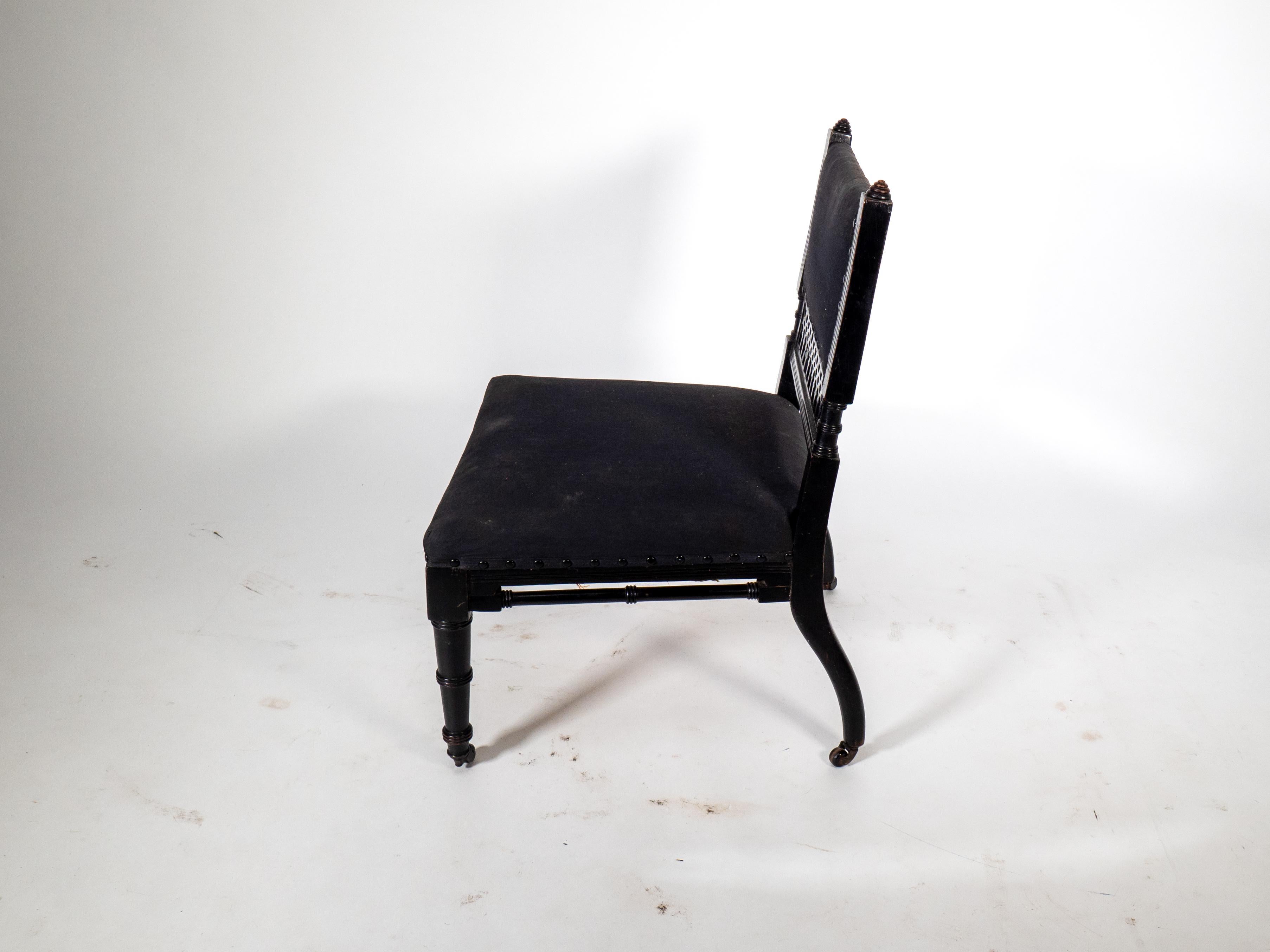 An Aesthetic Movement low side chair with fretwork to the lower back rest, this has shrunk and cracked a little but still quite useable. With unusual high, turned stretcher supports on ring turned front legs and original castors.