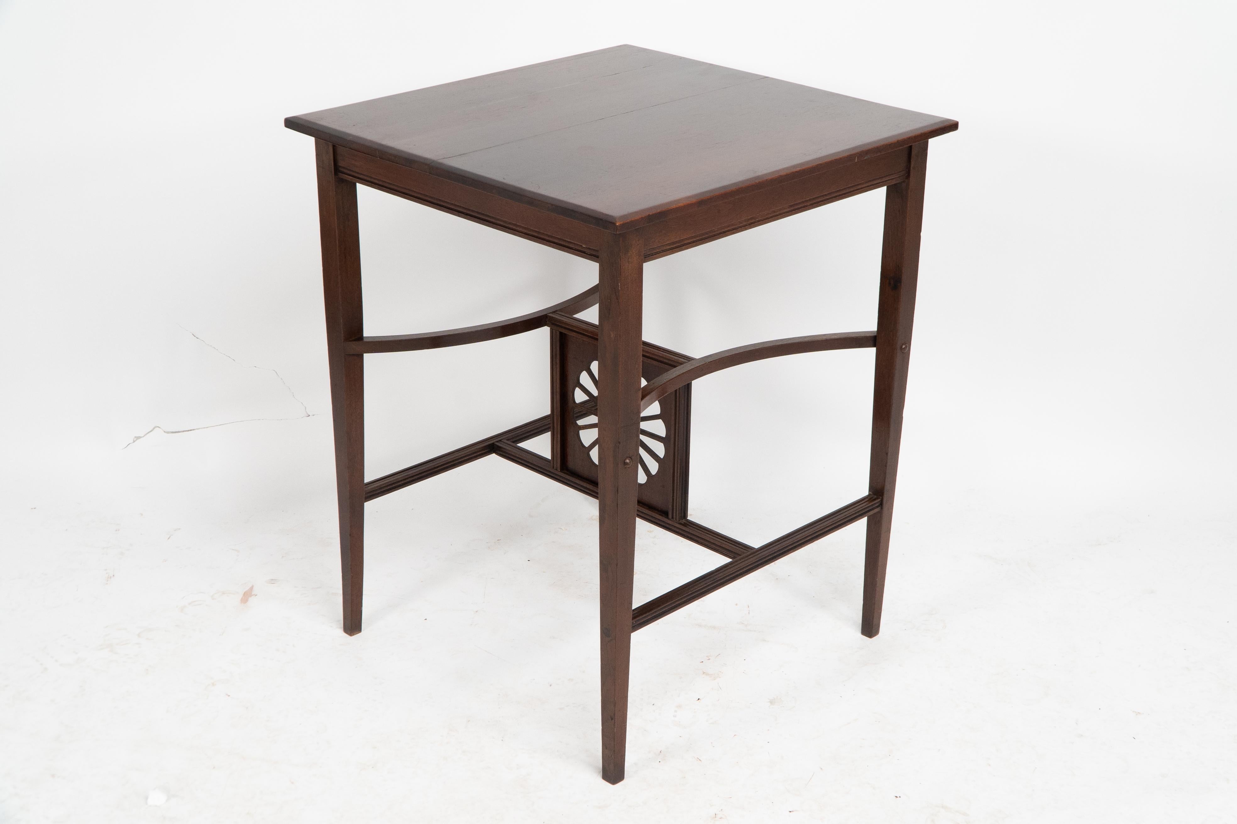 A rare Aesthetic Movement walnut side table with two curved upper stretchers that unite to a central sunflower and a lower straight sided H stretcher that unites to the bottom of the central sunflower which is inset into a frame with tramline