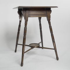An Aesthetic Movement side table with scroll supports stood on ring turned legs