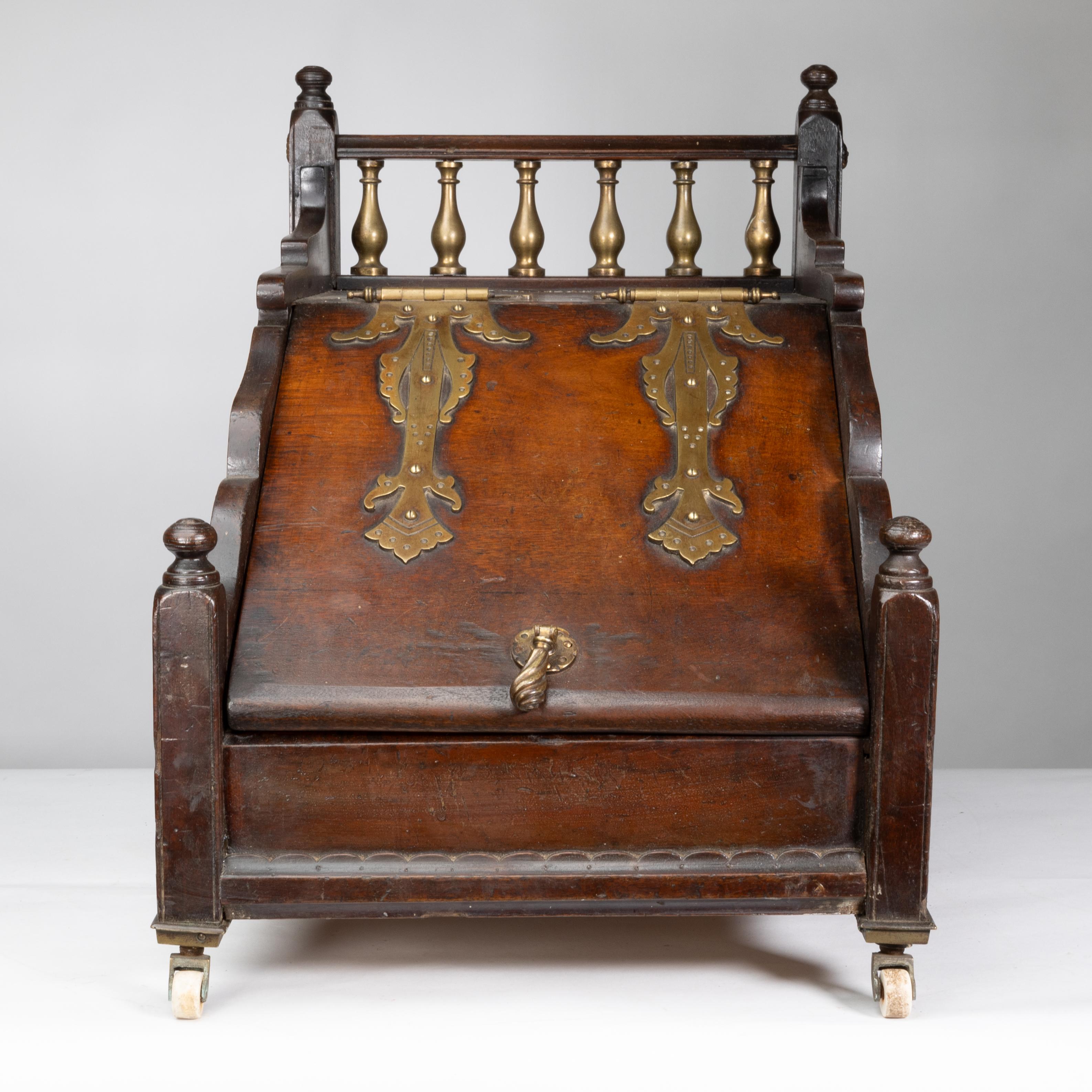 Scatola per carbone in noce dell'Aesthetic Movement con terminali torniti e una serie di torniture in ottone sul retro e cimette in ottone applicate. I fianchi presentano decorazioni floreali intagliate su pannelli in rilievo e piani sagomati, il