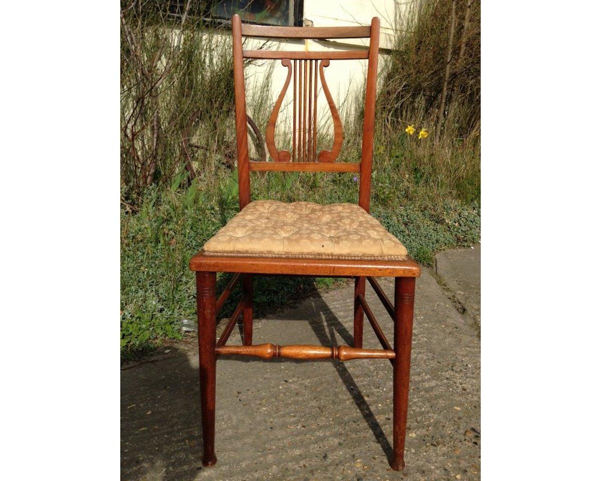 Silla de dormitorio con respaldo de lira de nogal del movimiento estético, en magnífico estado original, que conserva su asiento de botones original.