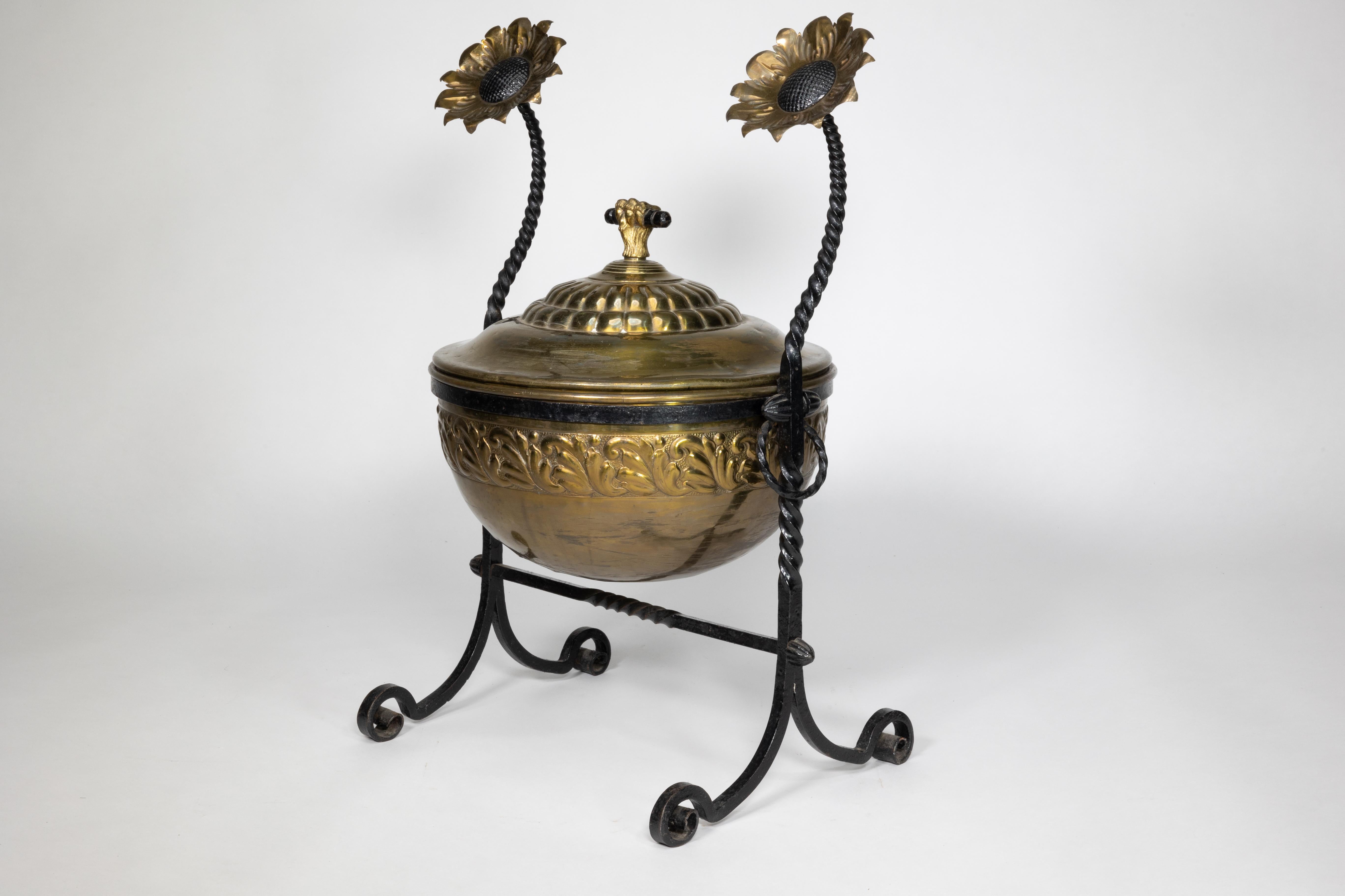 An Aesthetic Movement wrought writhen iron and copper fire bucket, with sunflowers that form a part of the main iron frame coming down to form the rim which holds the bucket in place, continuing down to the split iron legs united by a writhern