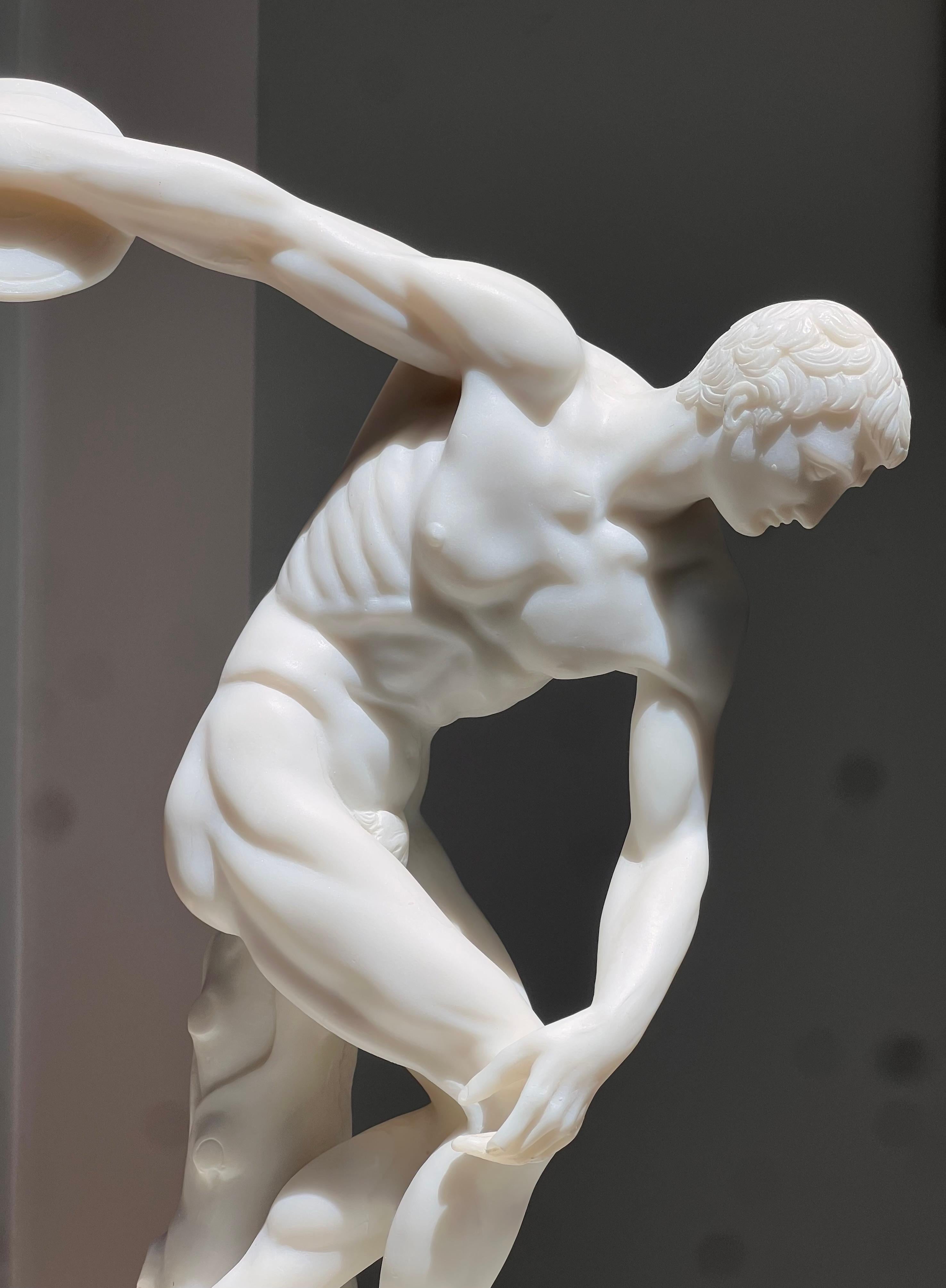 A handsome hand-carved alabaster style sculpture of an Olympian athlete preparing to hurl a disc, probably 20th century. Possibly soapstone or resin, but resembles alabaster. This stunning sculpture highlights the juxtaposition between fragility -