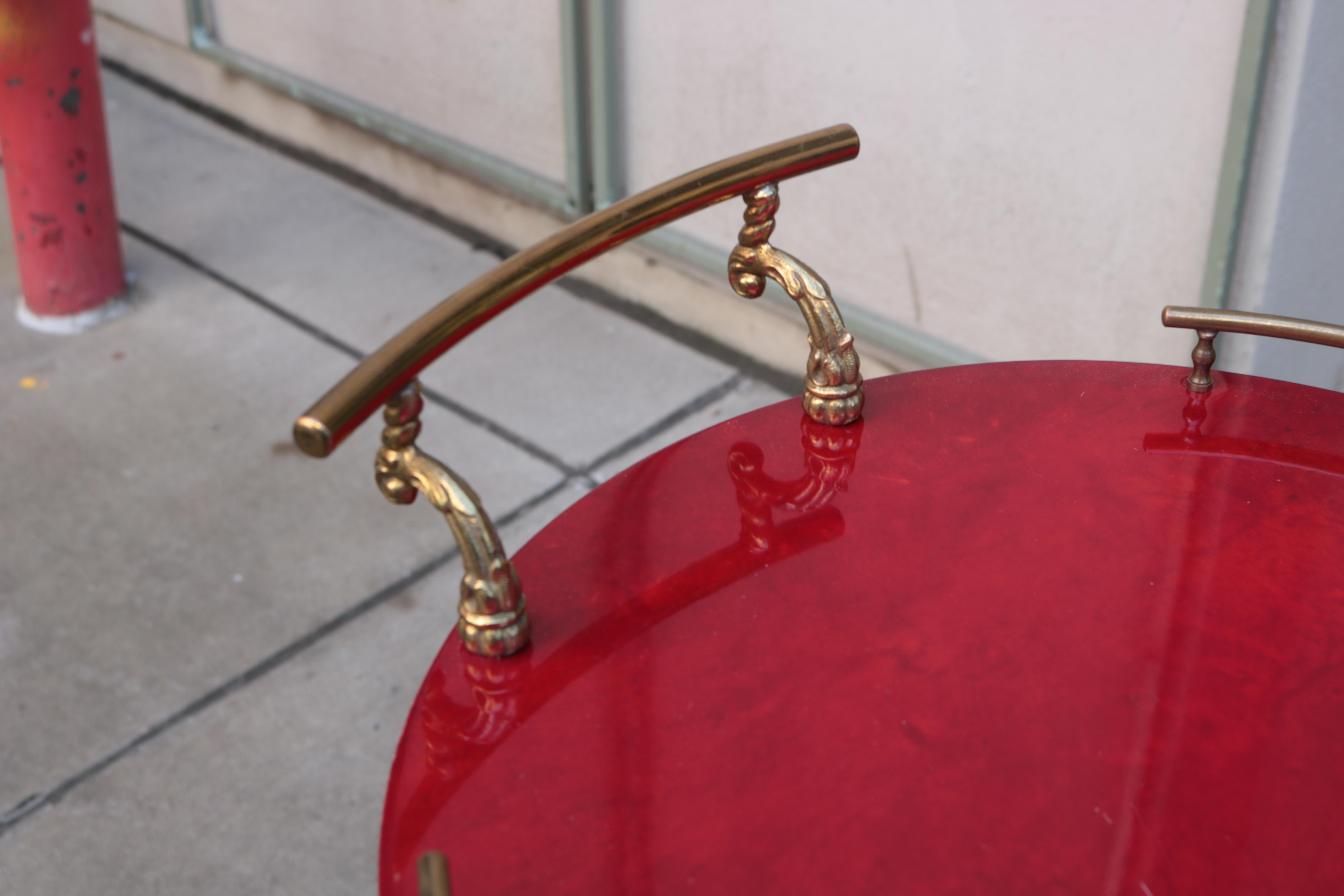 An Aldo Tura Modernist three tier bar cart. 
Patinated brass details and red lacquered parchment.
