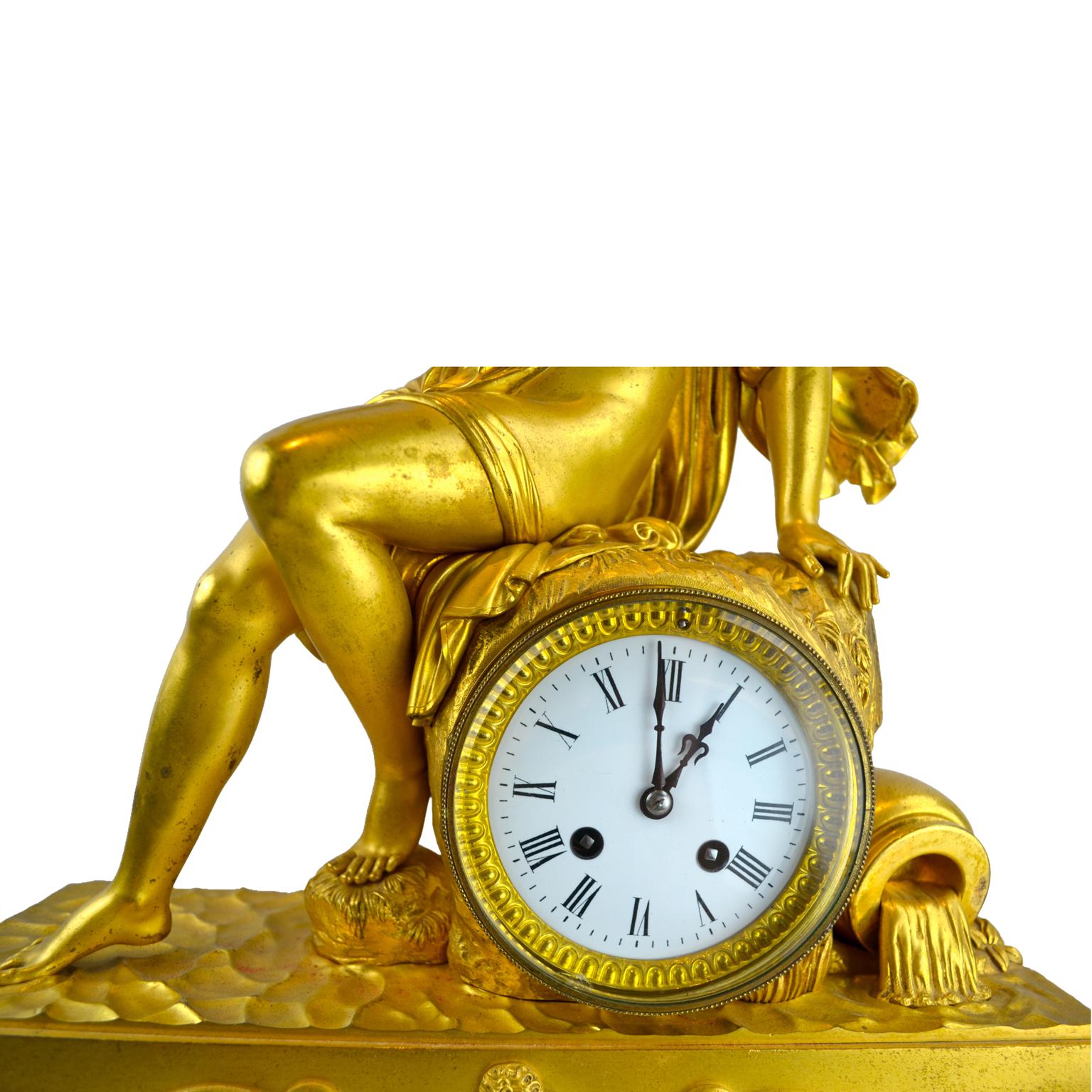 Eine vergoldete Bronzeuhr aus dem französischen Empire, die eine Allegorie auf die Wasserquelle der Erde darstellt. Auf dieser Uhr sitzt eine klassisch drapierte Nymphe auf einem Felsvorsprung, ihr rechter Fuß ruht auf dem Wasser. Rechts vom