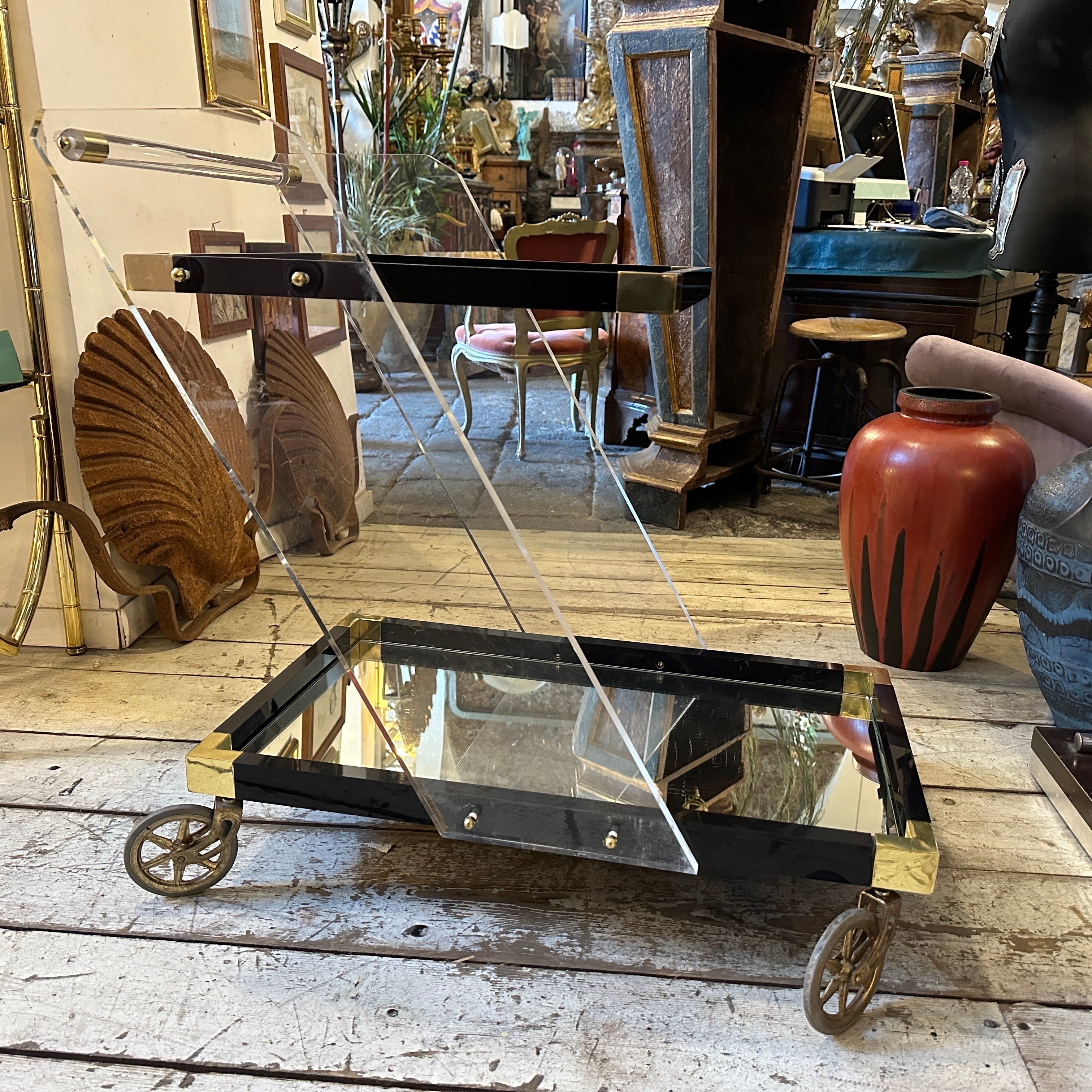 Un elegante carrello da bar in lucite e ottone disegnato e prodotto in Italia negli anni Sessanta, in buone condizioni con normali segni d'uso e d'età, il piano inferiore è in vetro specchiato, il piano superiore è in vetro trasparente, le parti