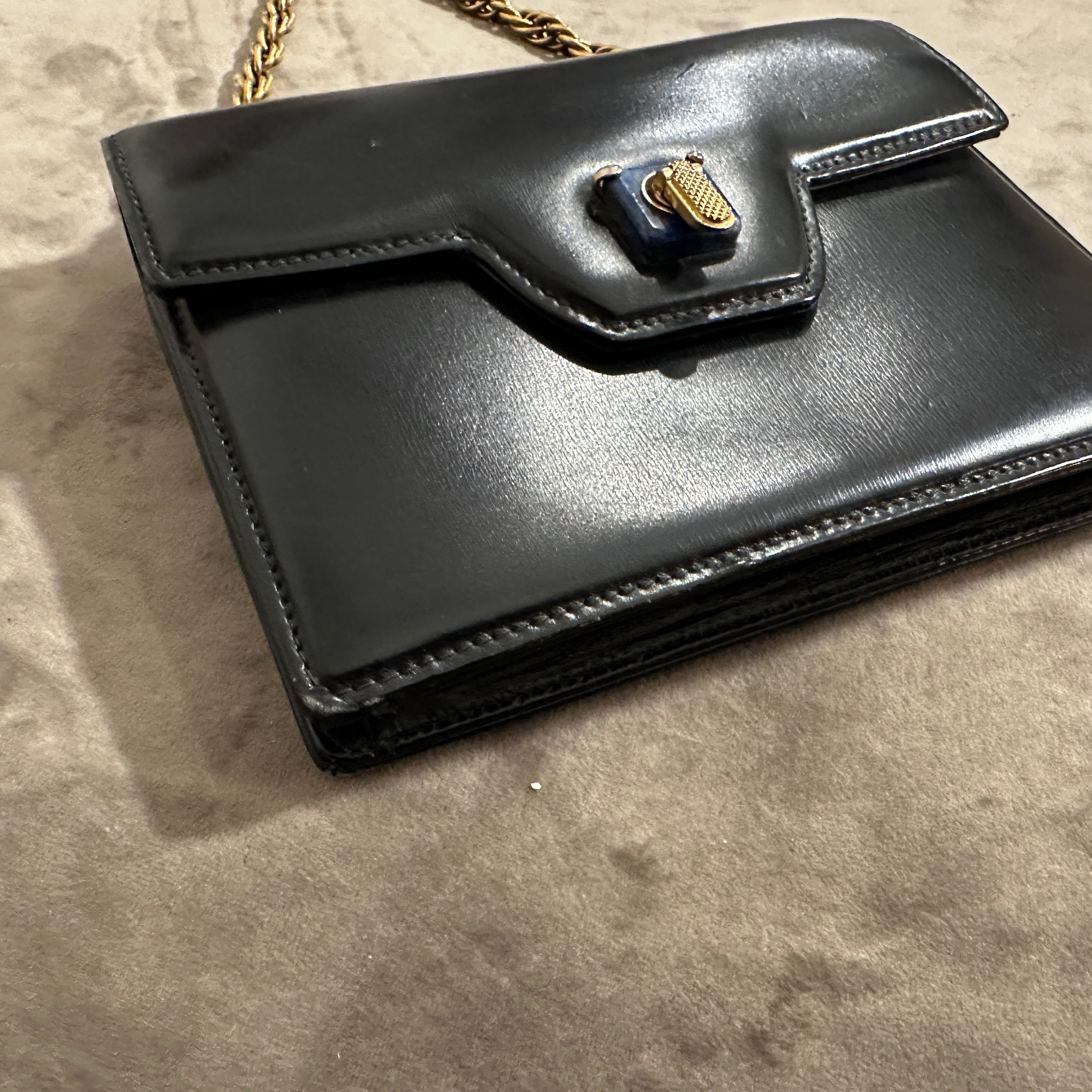 This is a stunning 1980s Gucci evening bar, crafted with blue leather and featuring an exquisite lapis lazuli clasp. Smooth and glossy deep blue leather, giving the bag a sophisticated and timeless appeal.
The structured, boxy silhouette with