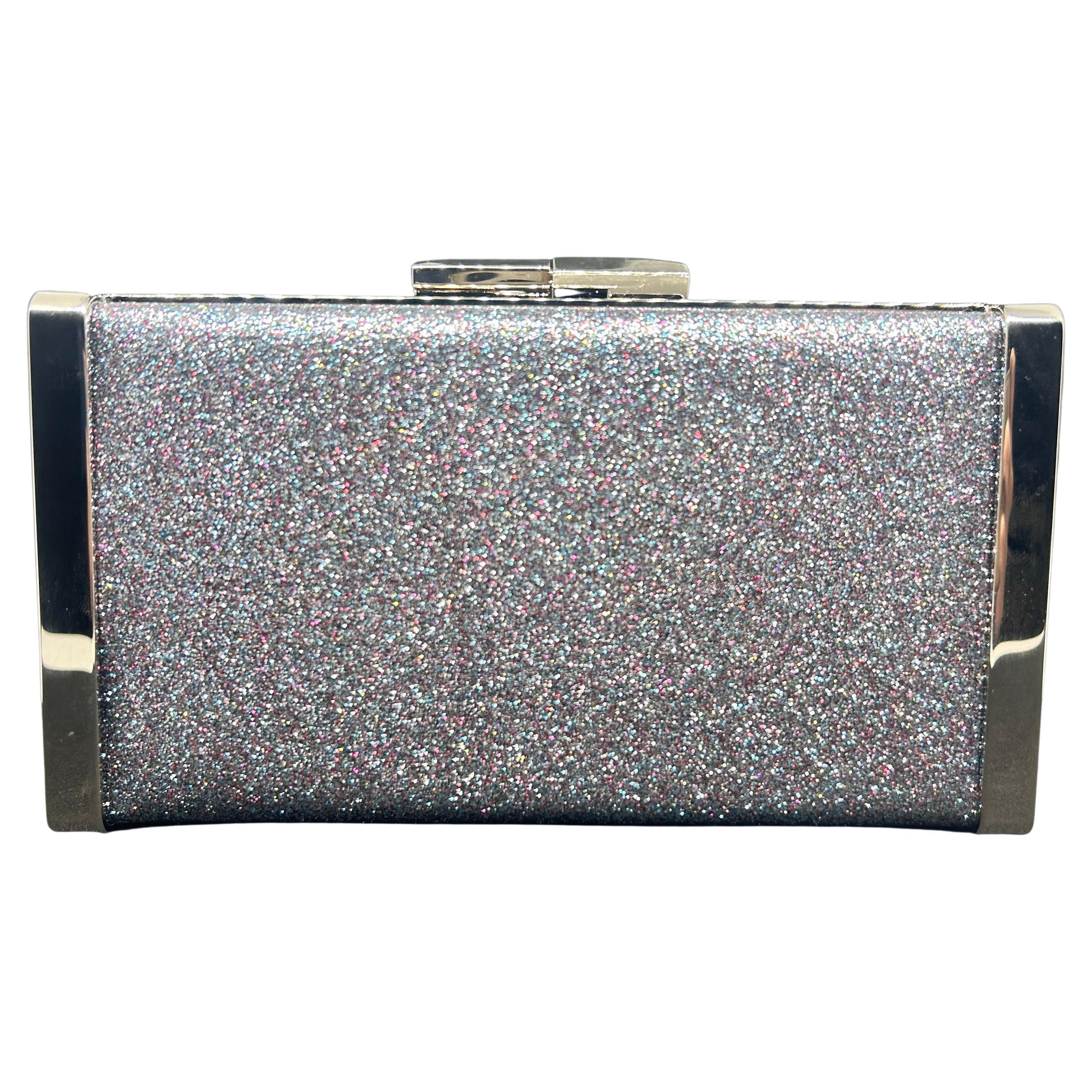 This Jimmy Choo ballet silver is crafted from fine glitter fabric and radiates elegance and sophistication. The sleek rectangular shape is enhanced by a shimmering silver glitter exterior that sparkles under the light, creating a mesmerizing effect.