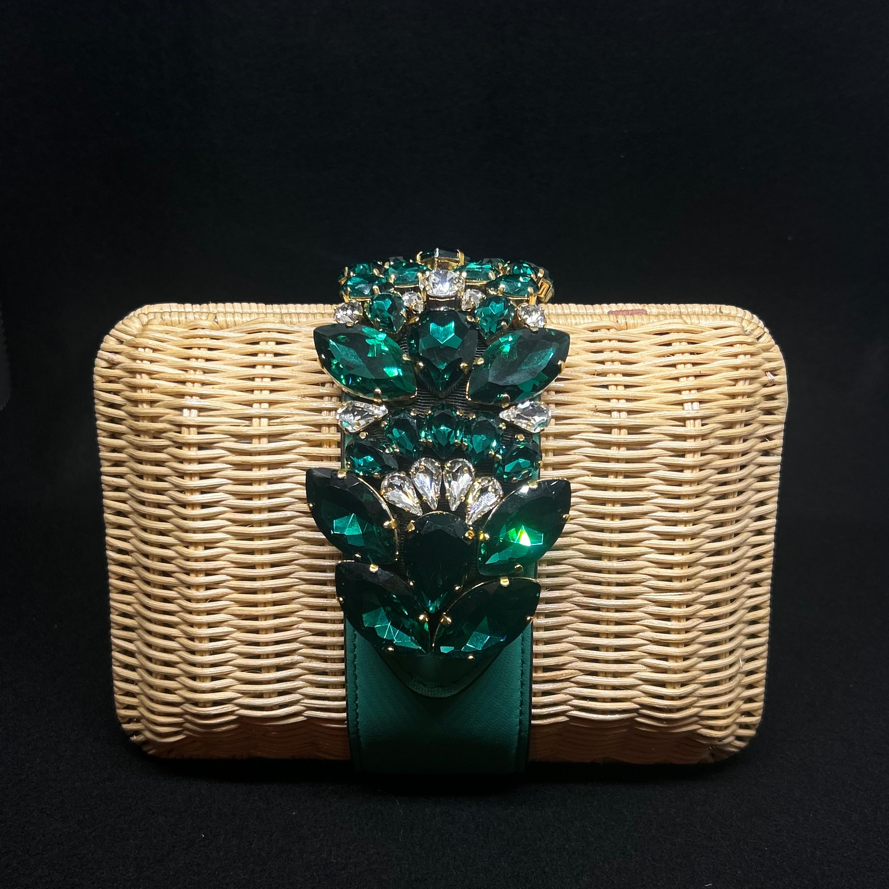 This Gedebe clutch bag showcases a unique combination of natural and luxurious elements, creating a standout, glamorous accessory.
The body of the bag is crafted from woven rattan, giving it a rustic, summery feel. This natural texture contrasts