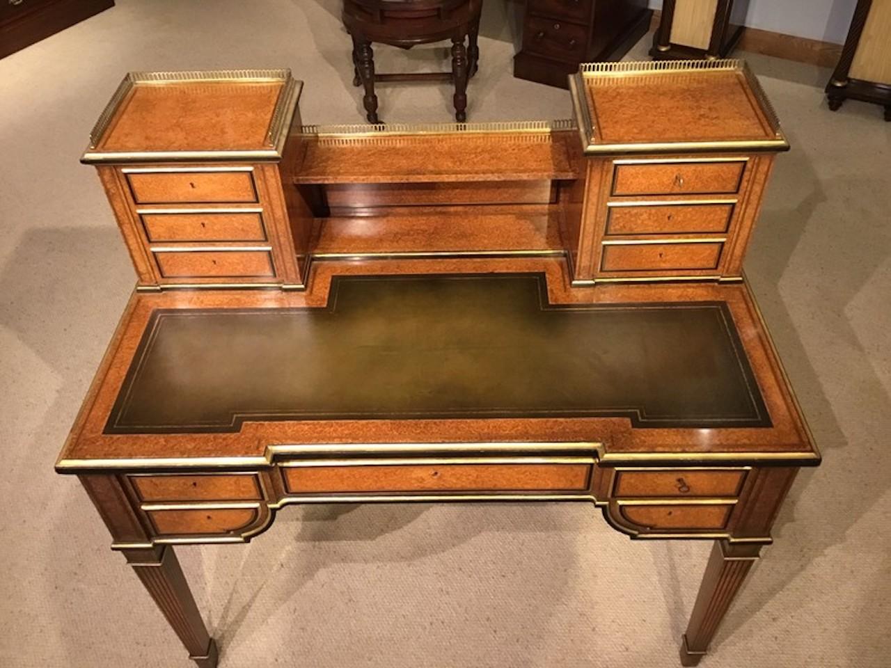 A rare amboyna, parcel gilt and ebony Victorian Period antique writing desk. Having a raised super structure with a brass gallery with six rectangular mahogany lined drawers and a shelf, veneered in the finest amboyna with parcel gilt detail and