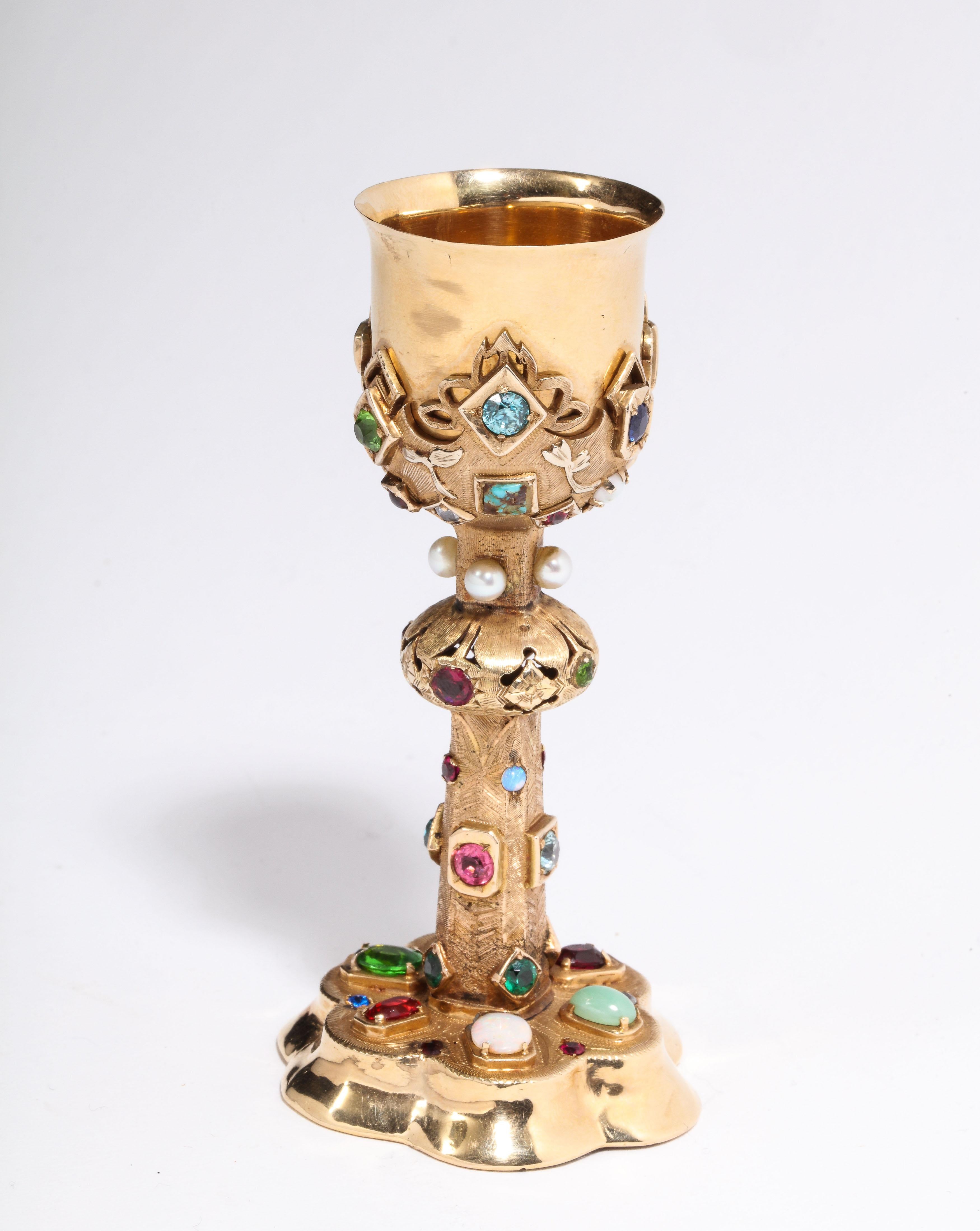 An American 14-karat yellow gold and semi precious stone miniature chalice cup, circa 1970.

Polished and brushed 14-karat yellow gold set with pearls, opal, jade, diamonds, and colored gem stones.

Measures: 4.5