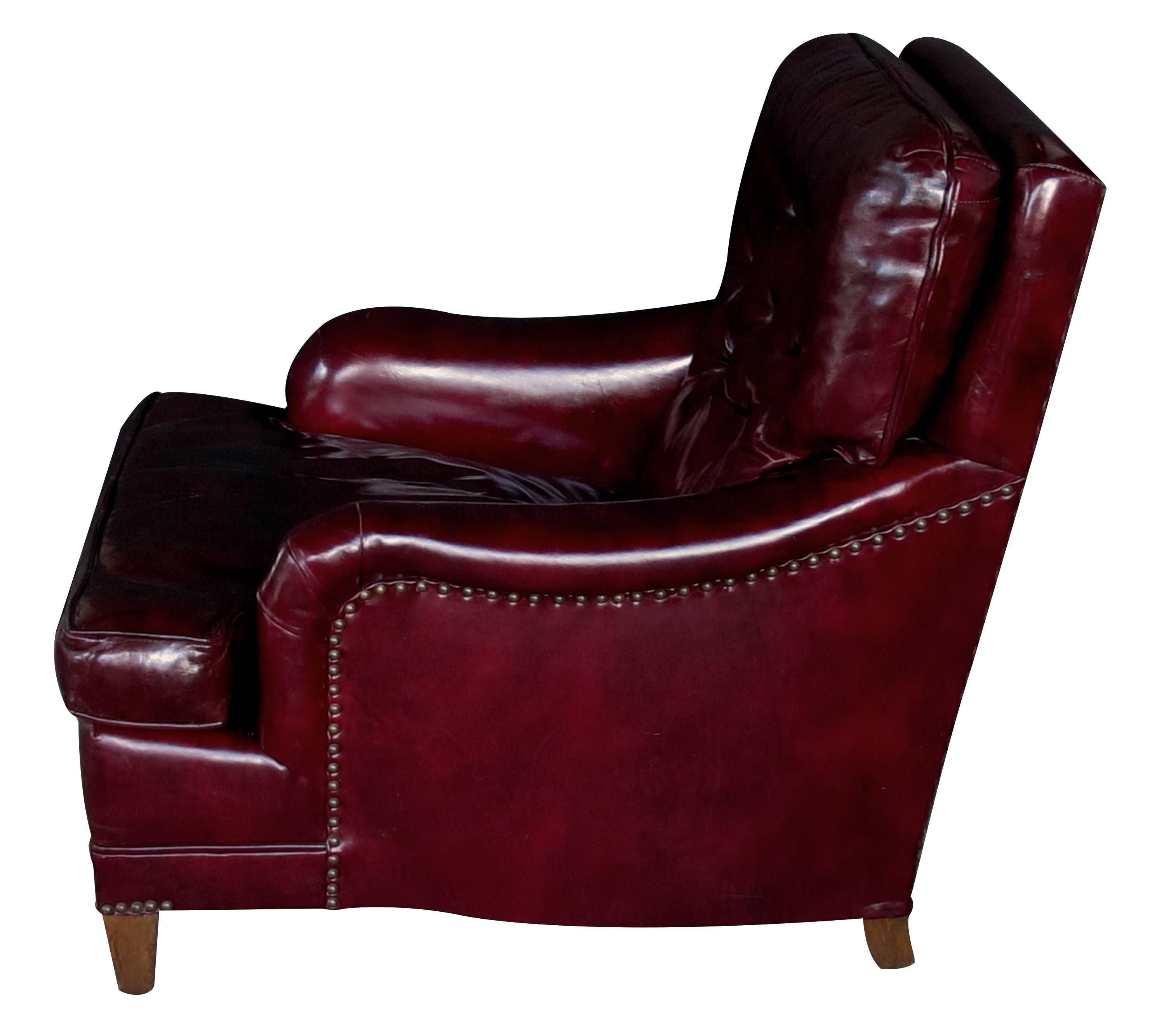 A handsome and comfortable American 1940s Chesterfield club chair and ottoman with deep burgundy leather; perfect for the den or library, the sumptuous club chair with tufted back and rolled arms; the matching ottoman with semi-detached cushion;