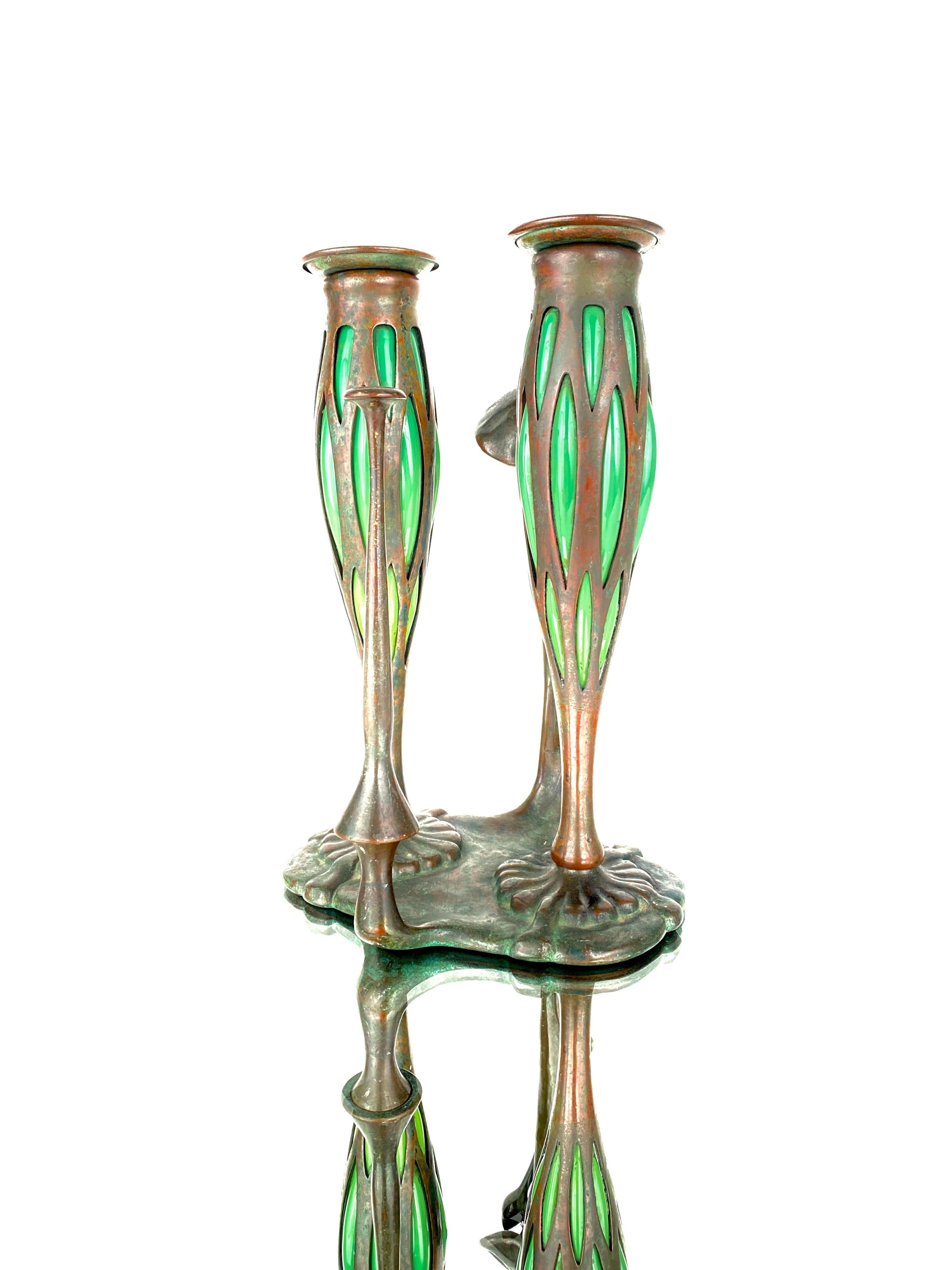 An American Art Nouveau patinated bronze and blown glass “Night Chamber” candlestick by, Tiffany Studios decorated with two over-sized green glass blown out candleholders atop an organic platform with mushroom and bud decorated handle. The