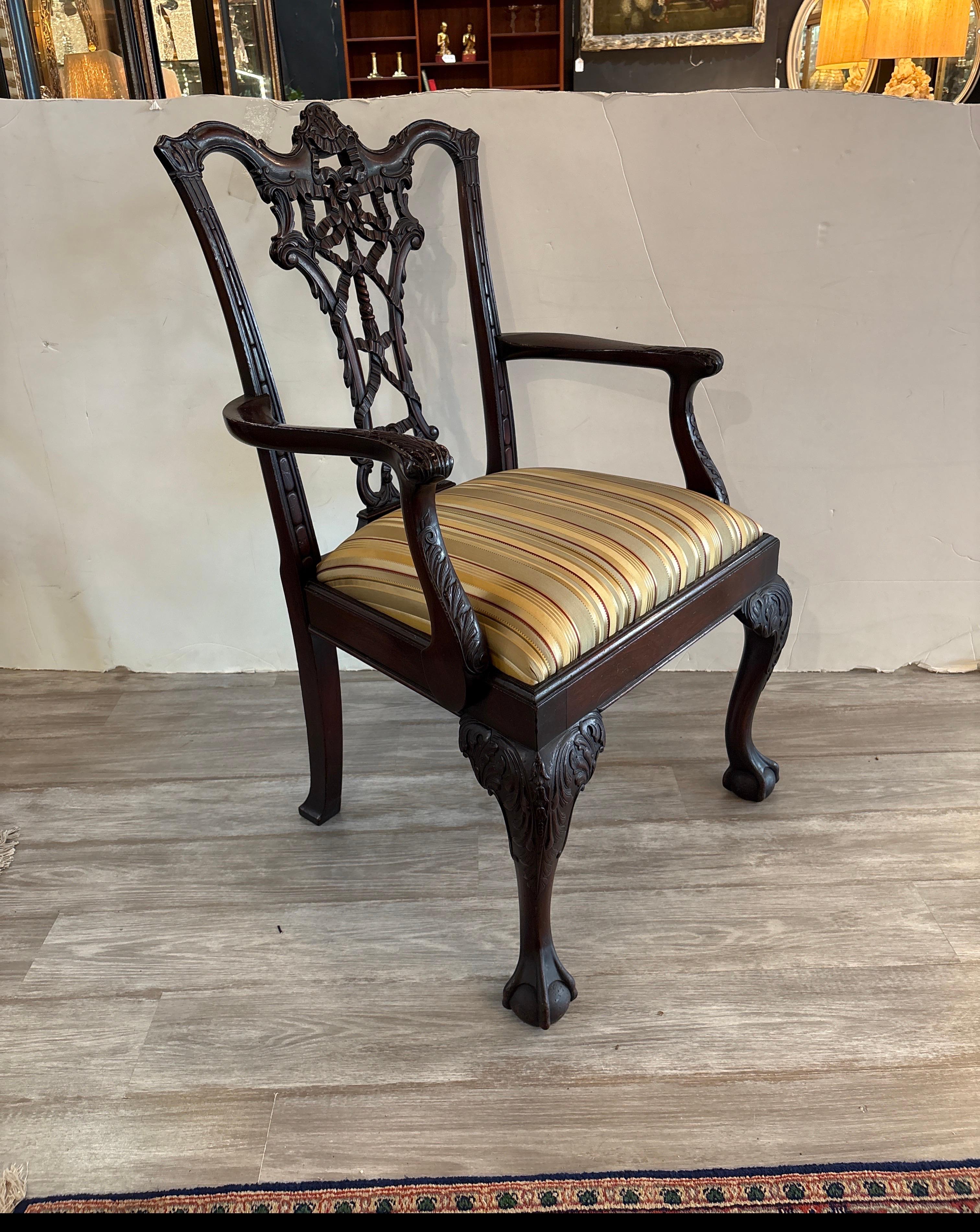Un clásico sillón chippendale de caoba tallado a mano. El robusto armazón tallado con todo lujo de detalles con un clásico respaldo de cinta chippendale, con el asiento recién forrado en una seda a rayas. Es una silla de acento o de escritorio