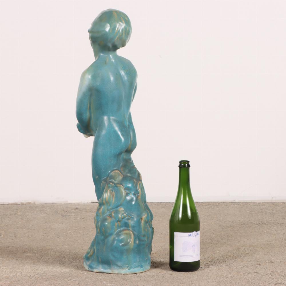 A charming glazed terra cotta figure of a boy, exquisitely modeled with lifelike detail and gentle expression. The figure captures a sense of innocence and quiet poise, with delicate features and a naturalistic posture with head leaning to