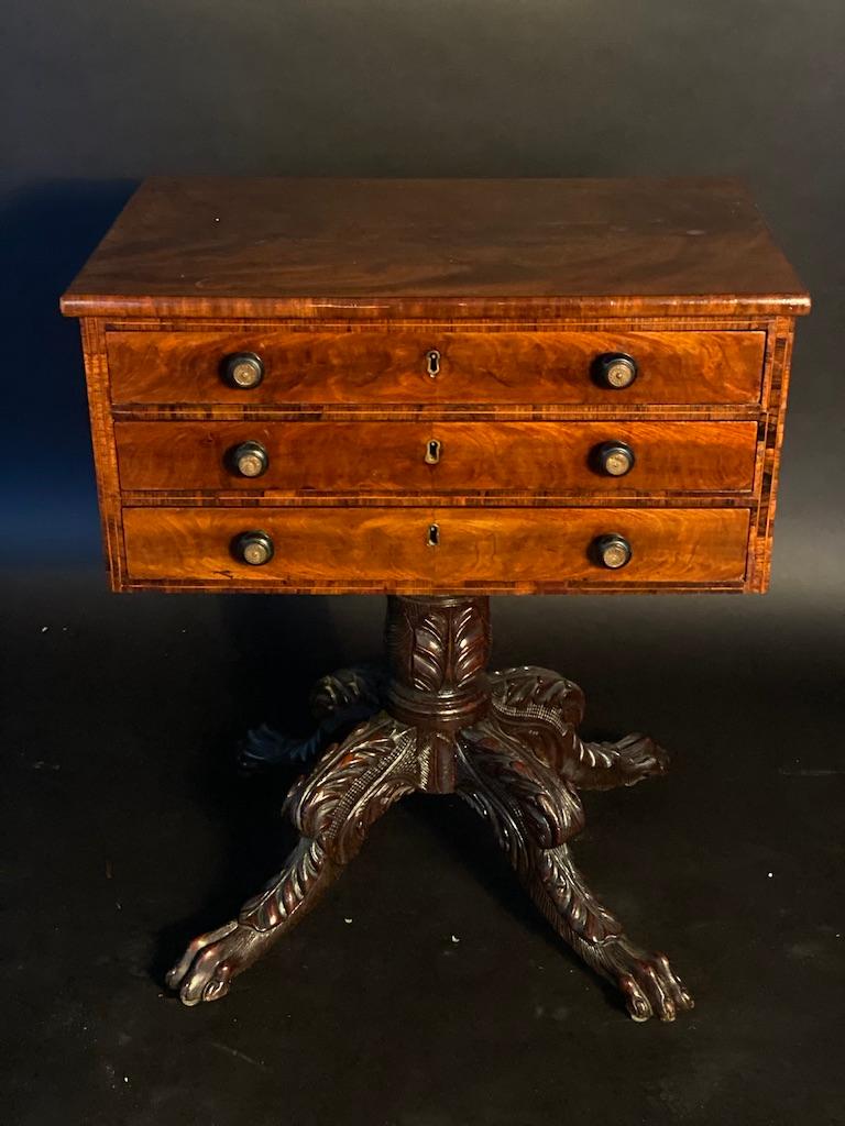 The cuban mahogany top above 3 drawers with original pulls, surrounded by fine line inlaid banding. The base in dark walnut richly carved with four animal legs, terminating in animal paw feet with 4 toes- all the quality woods and carving make this