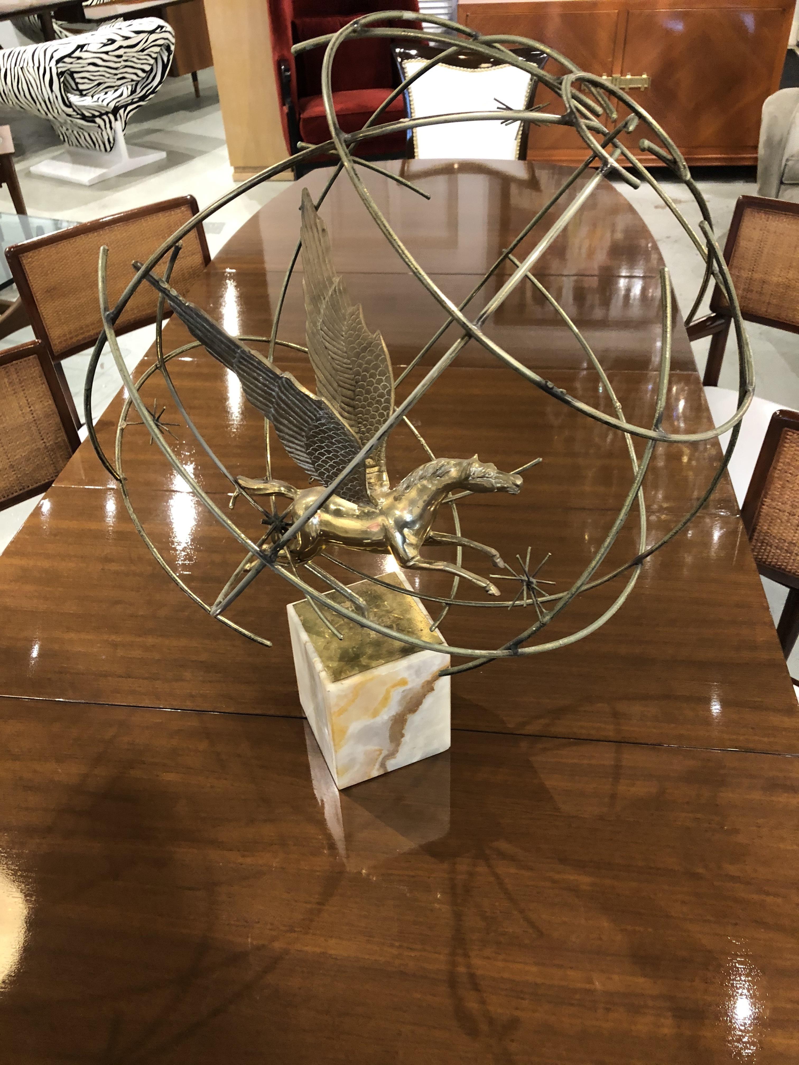 A very rare figurative sculpture of a pegasus, encircled by a globe. Only 10 of these were made. The globe has a very abstract feeling with small clusters of starbursts on the structure. the brass sculpture sits atop a square marble base.