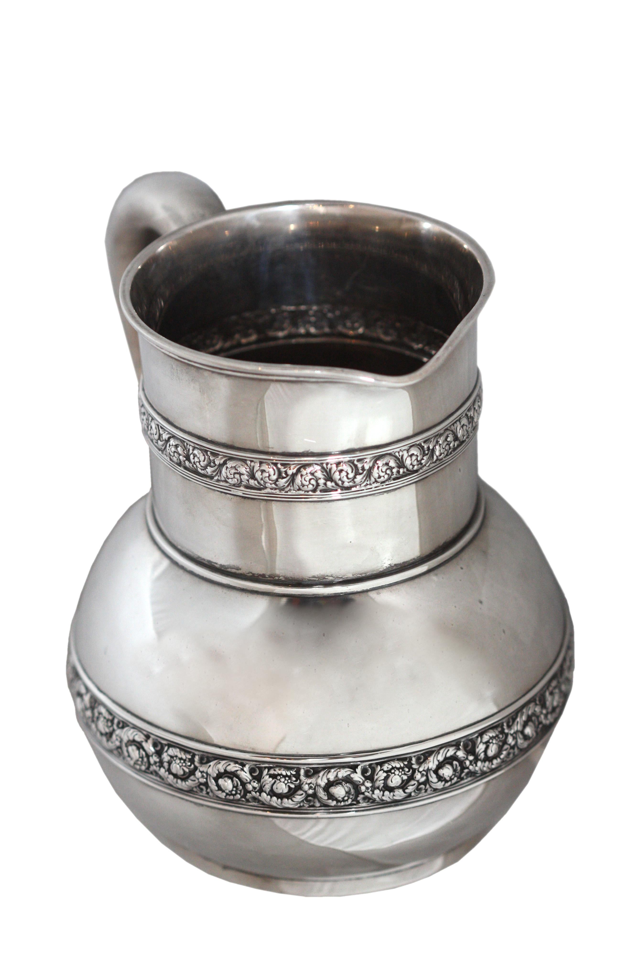 An American silver water pitcher, Mark of Tiffany & Co., New York,
1891-1902
applied with bands of scrolling foliage, flowers, and shells, the handle plain
marked on base
Tiffany & Co
Sterling Silver
and numbered 8077-4155
26 oz
749