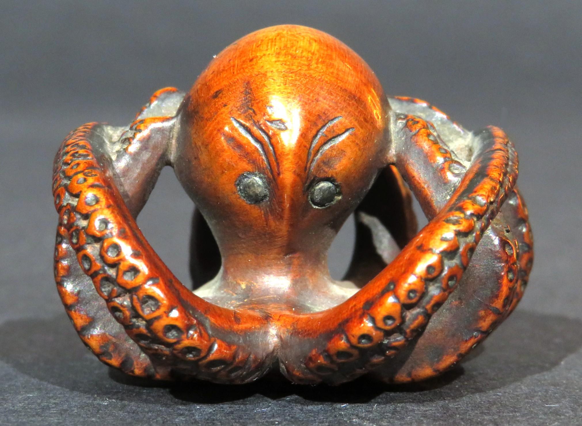 The hand carved & stained boxwood netsuke deftly rendered in the form of an octopus with somewhat anthropomorphic features, showing black stained eyes & furrowed brow effecting an amusing, somewhat angry humanistic expression. Each of the eight