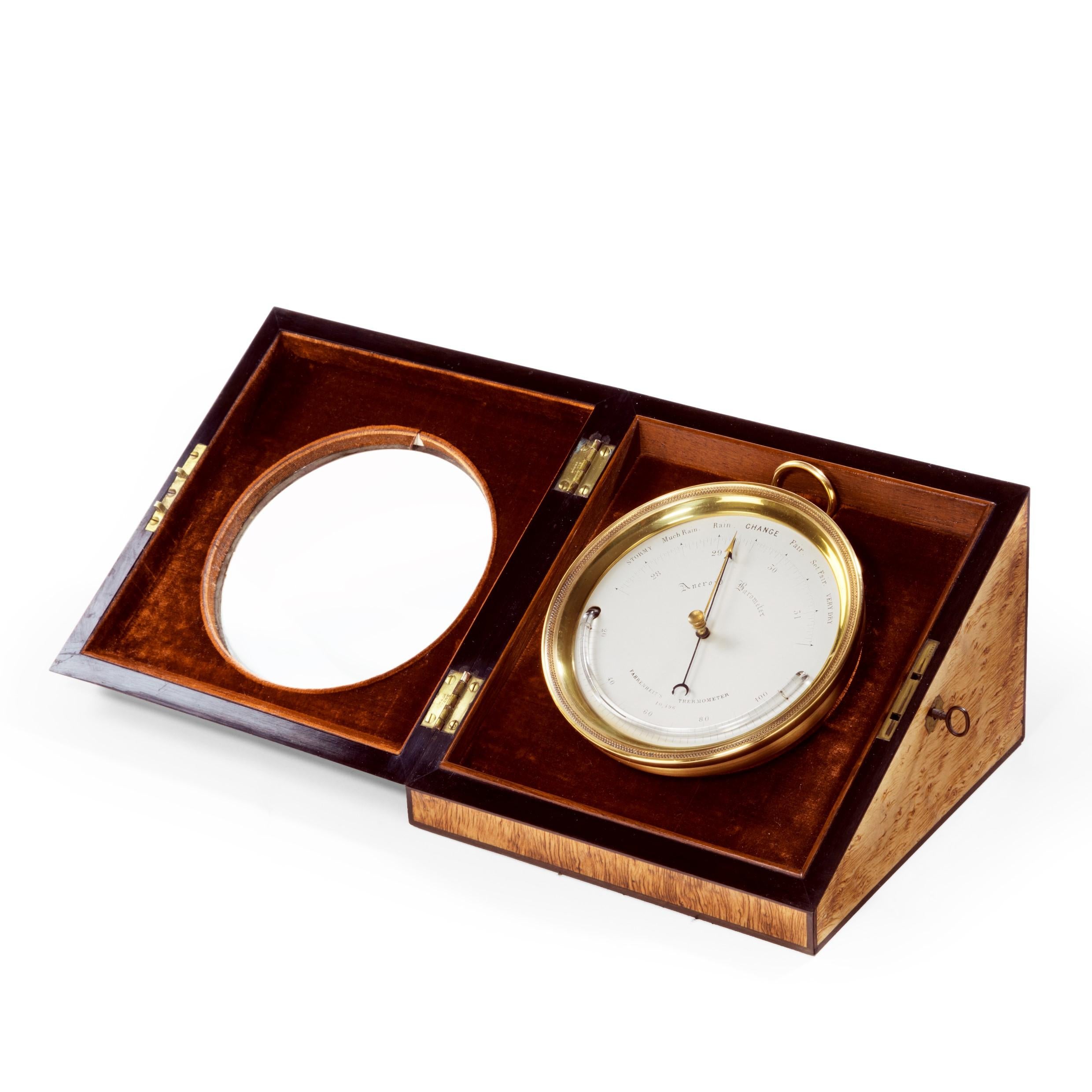 An aneroid desk barometer by C W Dixey, the 4inch silvered dial with blued indicator and gilt recorder needles divided to 32 millibars, with curved bar Fahrenheit thermometer, the gilt brass case engraved ‘Sold by C. W. Dixey, Optician to the Queen,