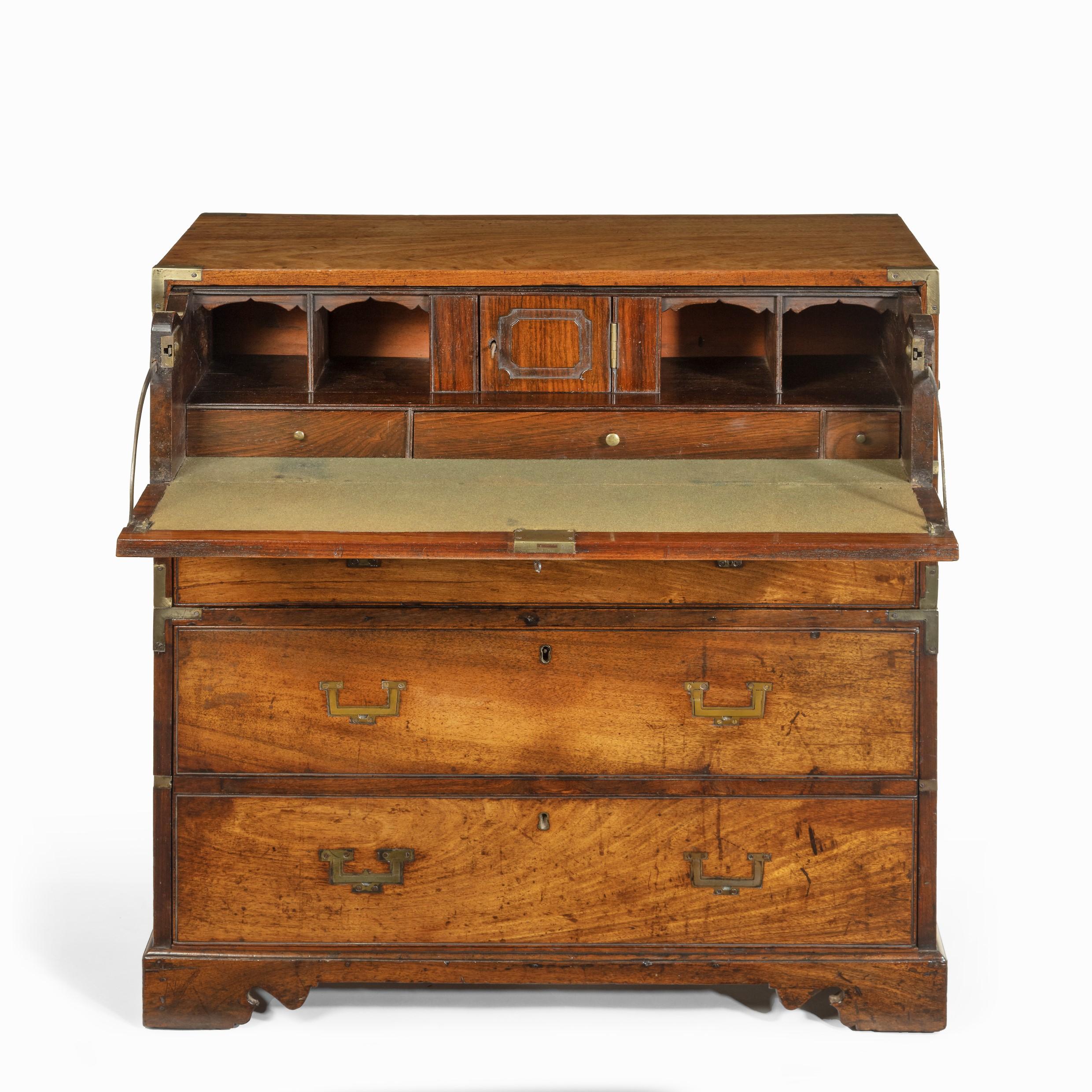 An Anglo-Chinese hardwood naval officer’s campaign chest. This chest (probably padouk) is of typical rectangular form, in two brass-bound sections with black-painted carrying handles on the sides. The top section has a fitted secretaire drawer above