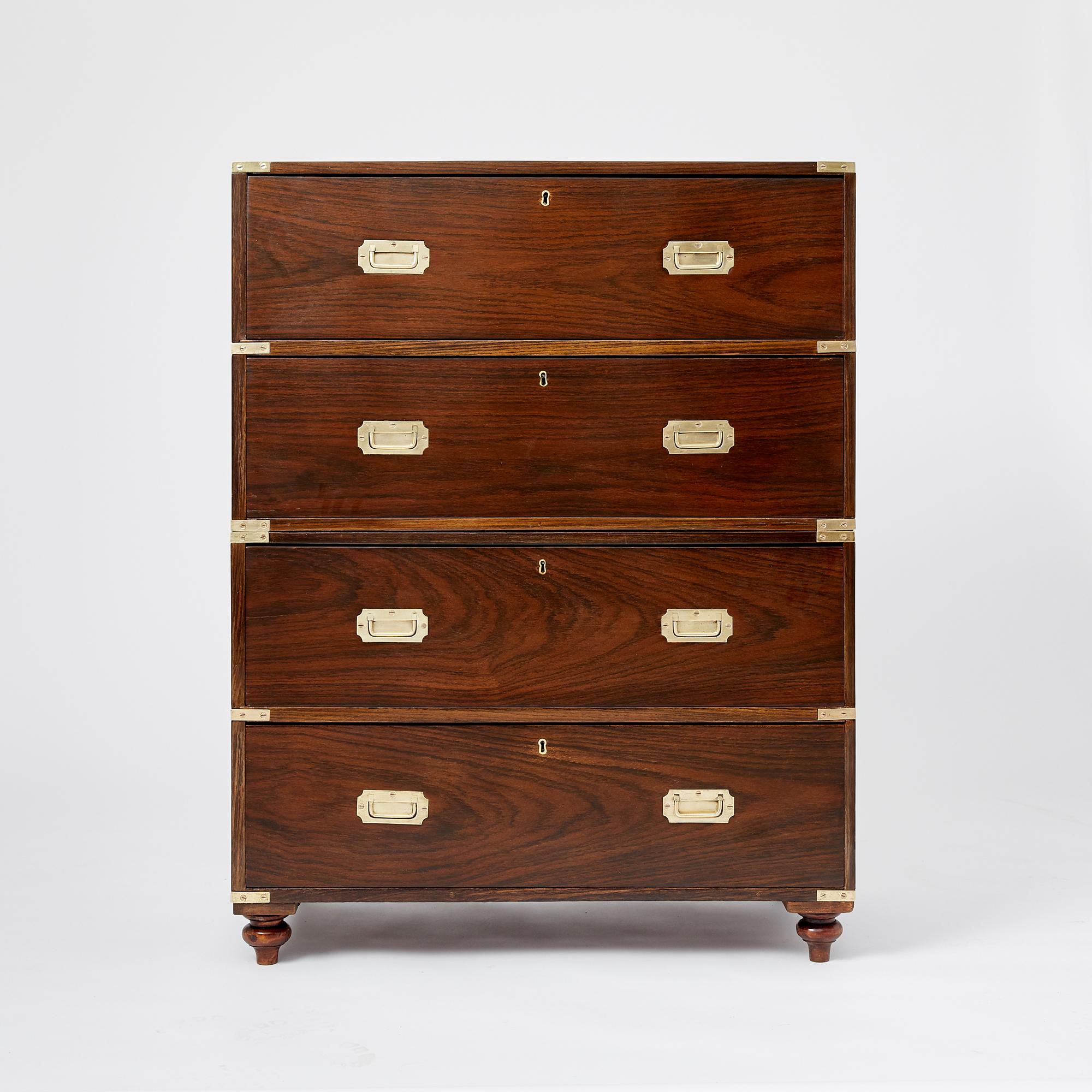 A two-part rosewood Anglo Indian campaign chest. Each section fitted with recessed brass handles on each side and protective brass corner mounts. Each drawer front with two recessed pulls. The base supported by turned rosewood legs. This piece is