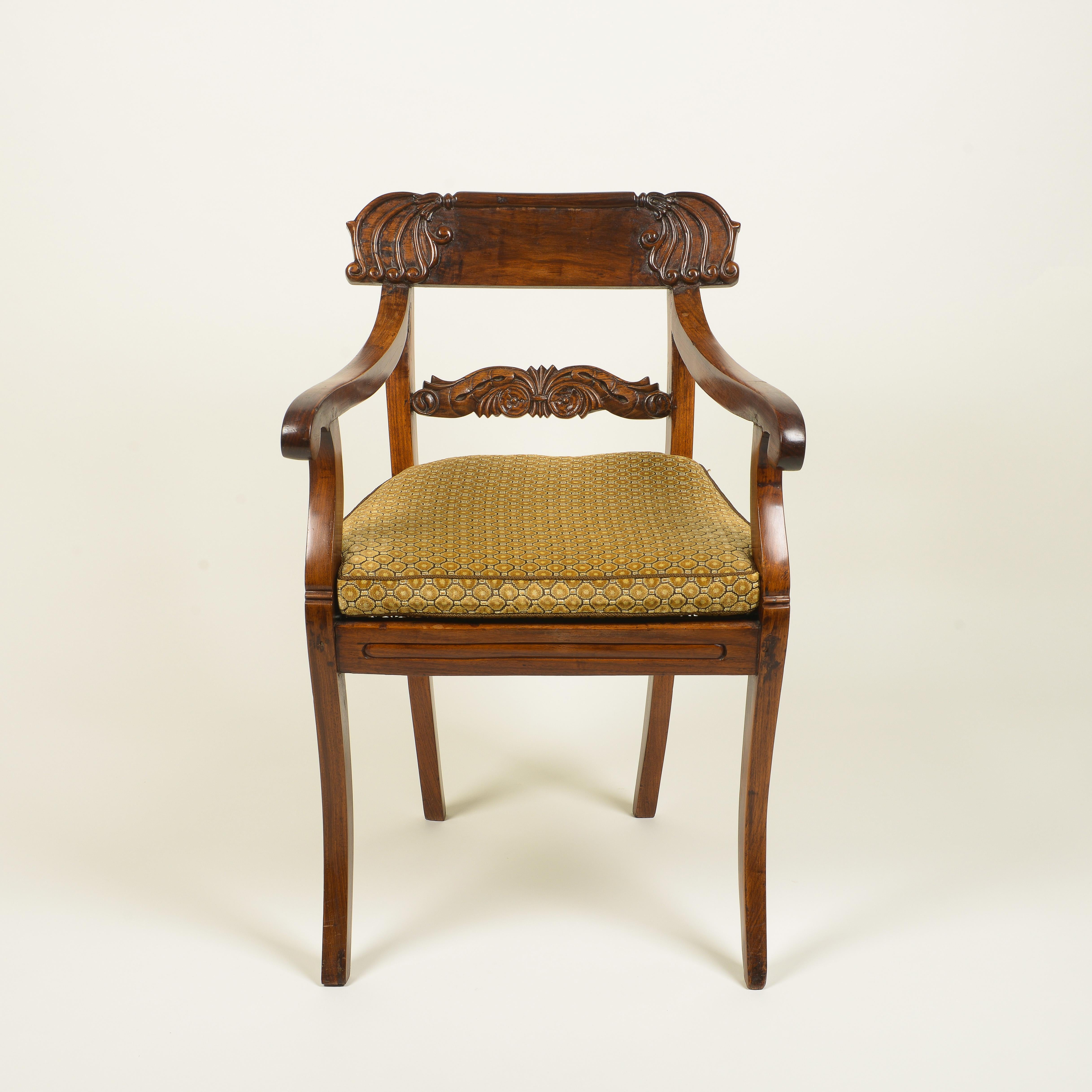 The tablet form crest rail carved with stylized scrollwork over a scrolling backsplash; with downward scrolling armrests; with cut-velvet gold loose cushion over a hand-caned seat; with channeled seat rail over sabre legs.