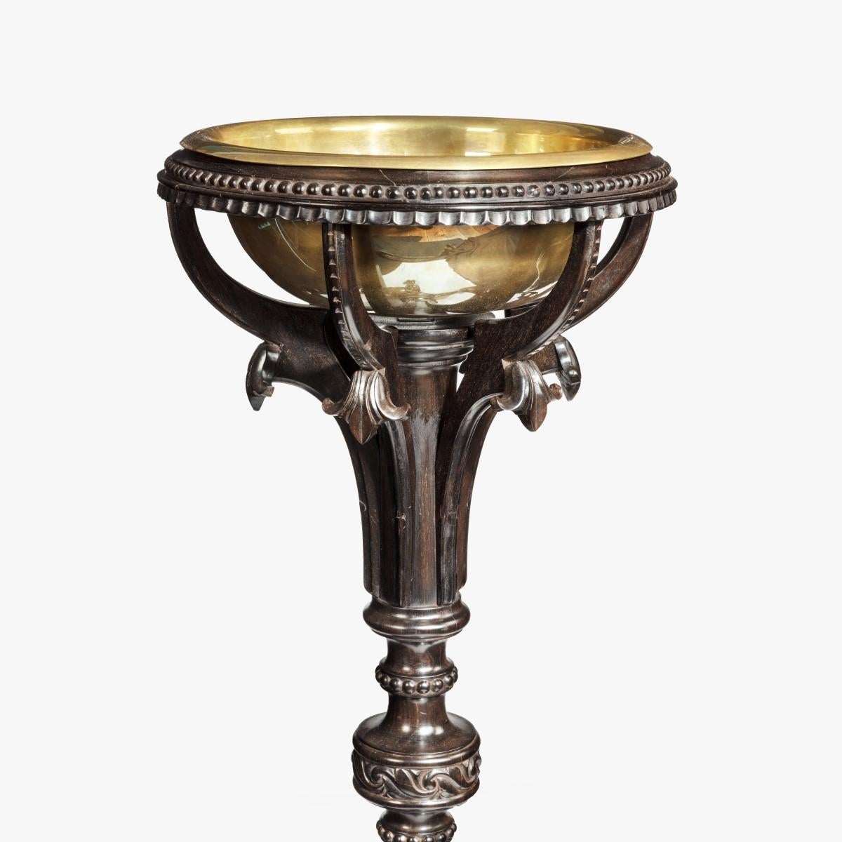 An Anglo-Indian solid ebony jardiniere, the circular brass bowl (replaced) set into an ebony tripod base with a turned, knopped support on three elephant-head feet. Indian, circa 1830.