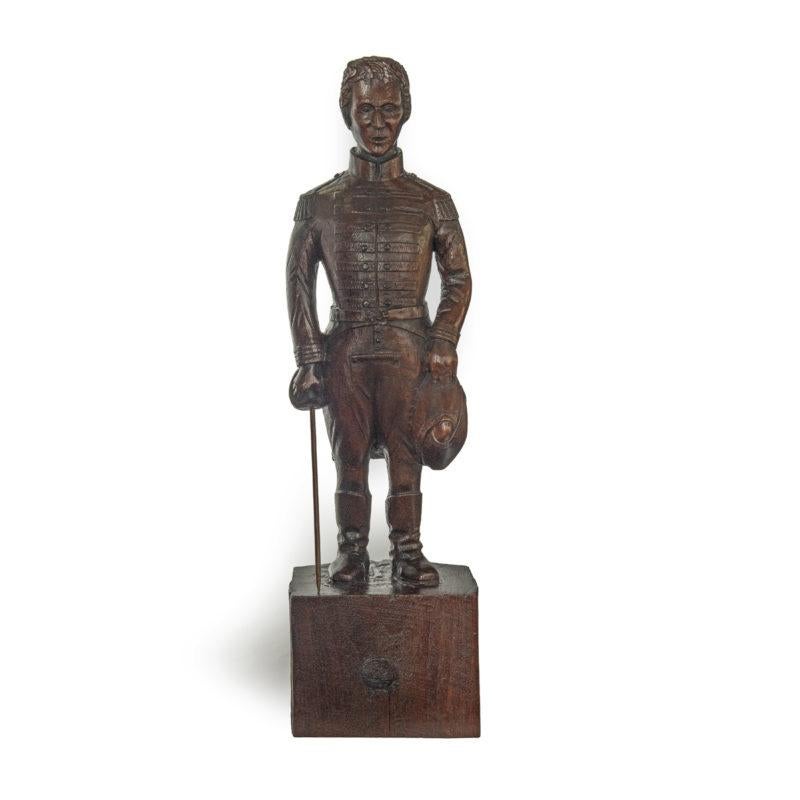 This naïve likeness is carved from a solid teak block.  The head has deep set eyes and a distinctive beaked nose.  He is wearing a tailcoat with seven rows of frogging and tasselled epaulettes, calf length boots and carries a sword and bicorne.  The