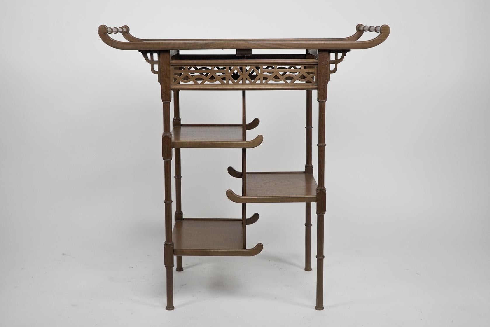 Heals and Son. An Anglo-Japanese beech wood side table with pagoda style turned rail to the upper ends, with Japanese style fretwork panels below, and three pagoda style shelves supported through each side in a stepped formation, supported on