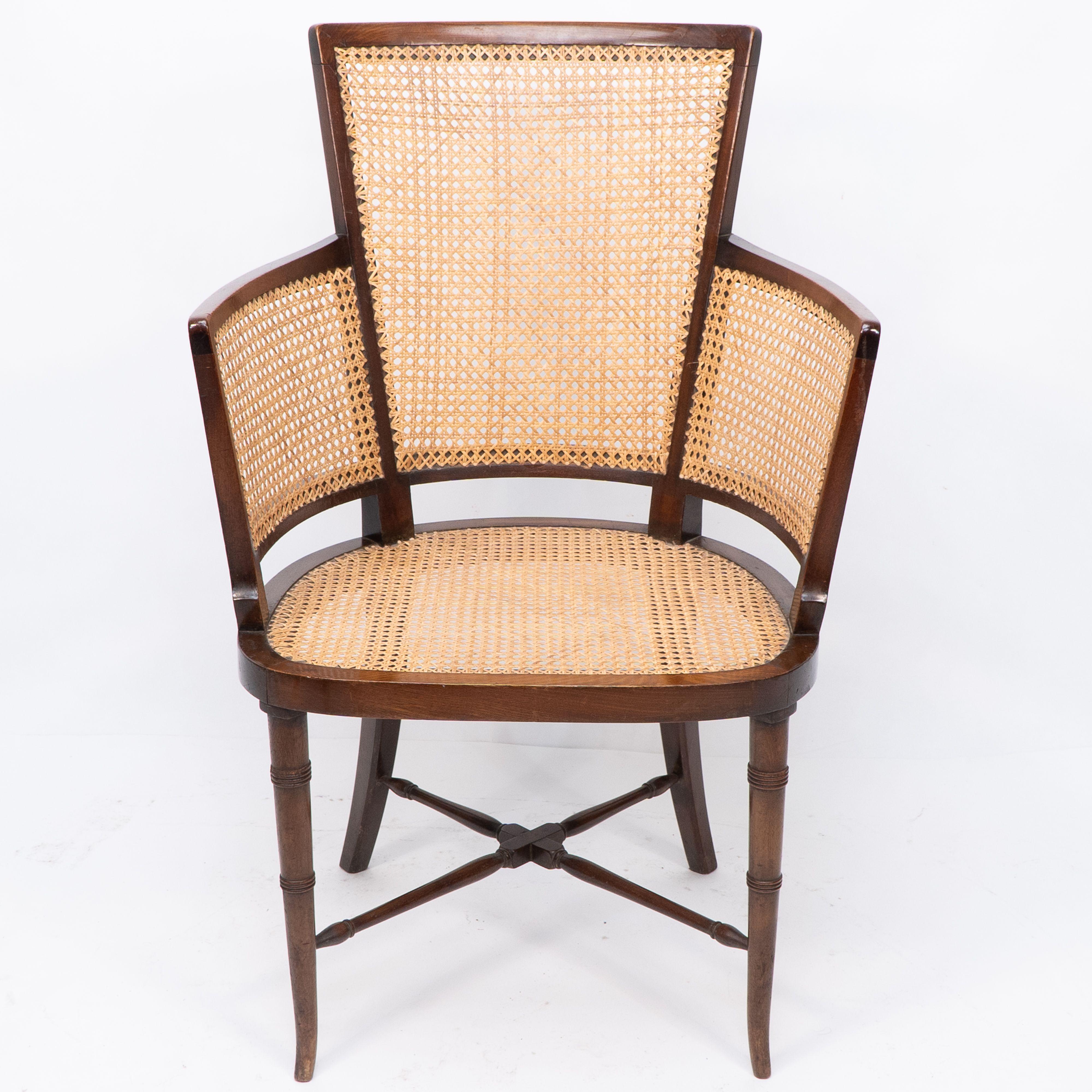 Fauteuil anglo-japonais en cannage avec un dossier incurvé et des pieds tournés en bambou simulé sur des pieds évasés.