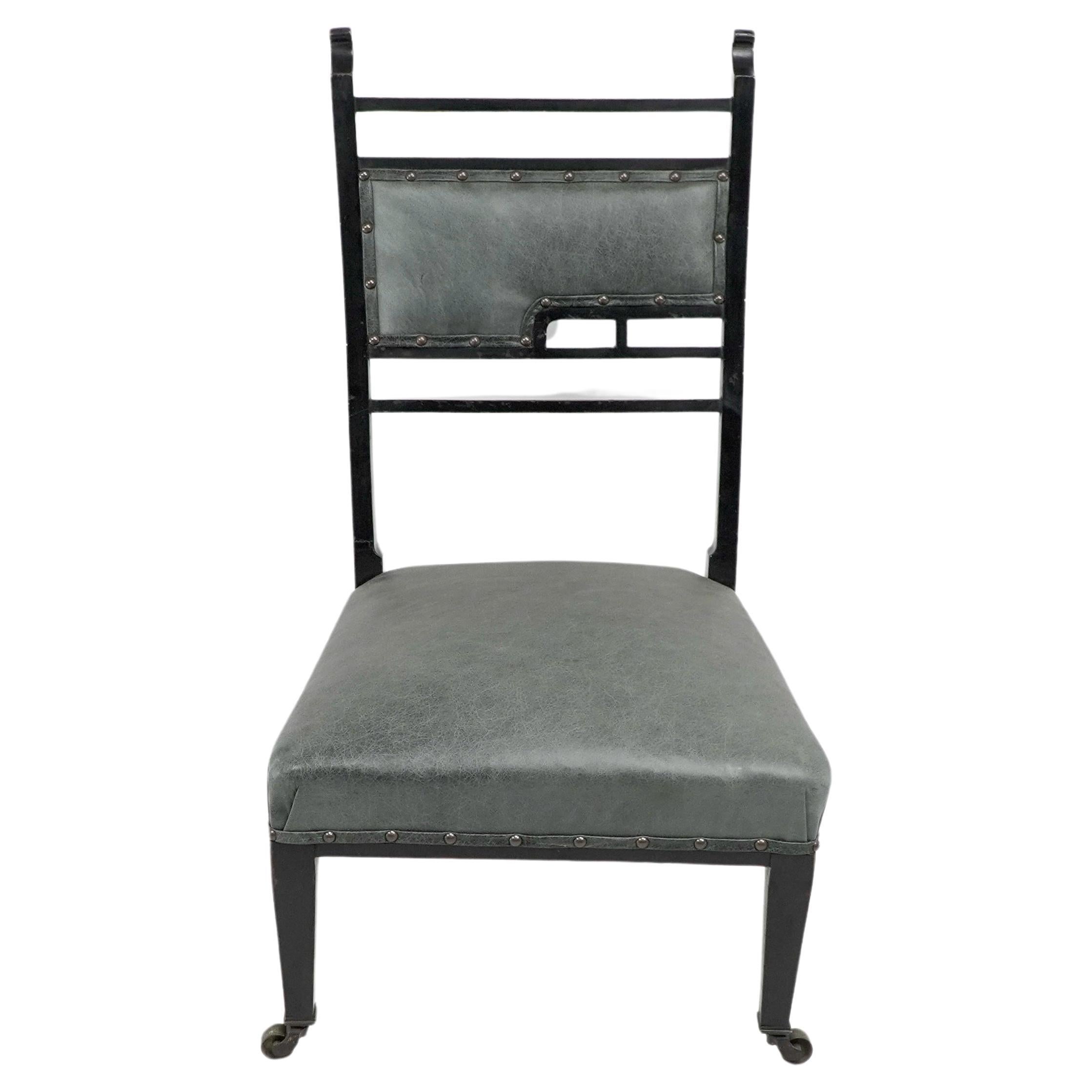 An Anglo-Japanese ebonized side or nursing chair with curled finials and subtle fret works to the back. Professionally reupholstered in high quality green hide.
