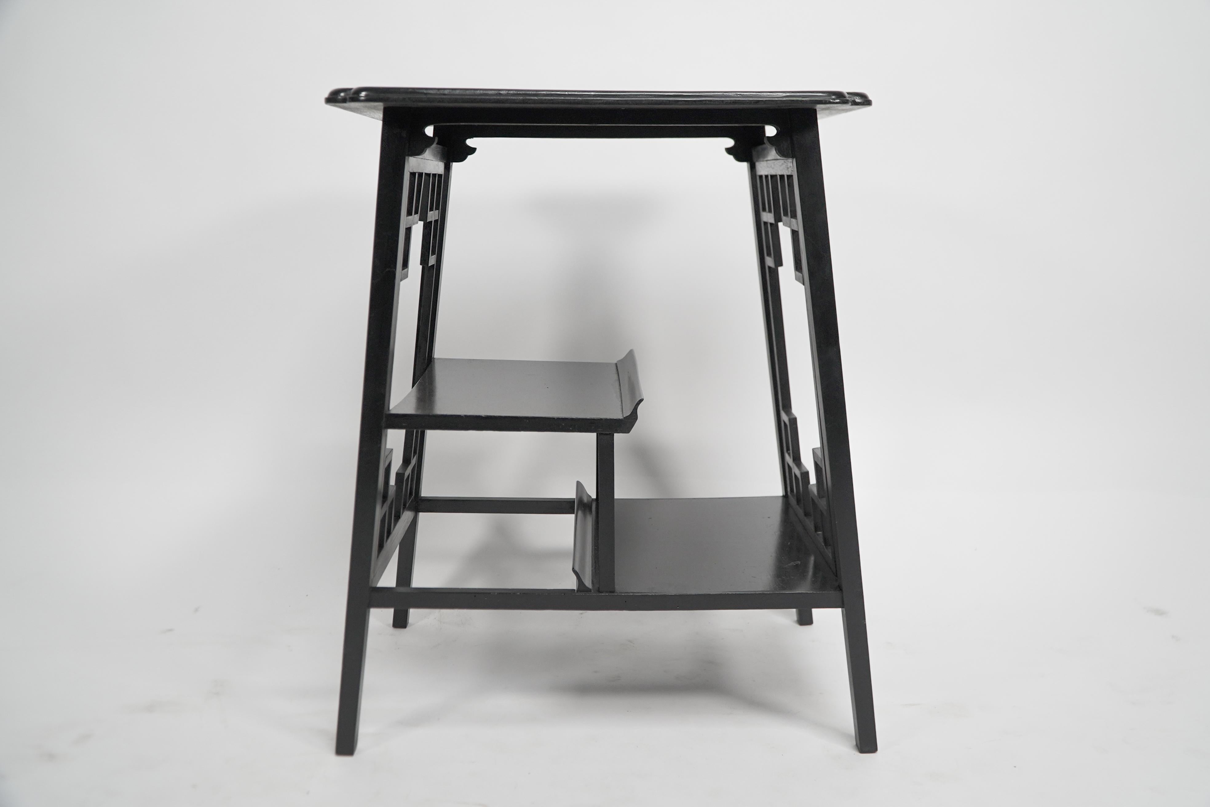 George Watson of Edinburgh. An Anglo-Japanese ebonized side table with hand carved edges to the shaped tops, lattice end panels, stepped display shelves, with a pagoda style curved edge.