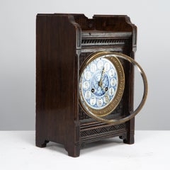An Anglo-Japanese carved oak mantel clock with hand painted blue floral dial.