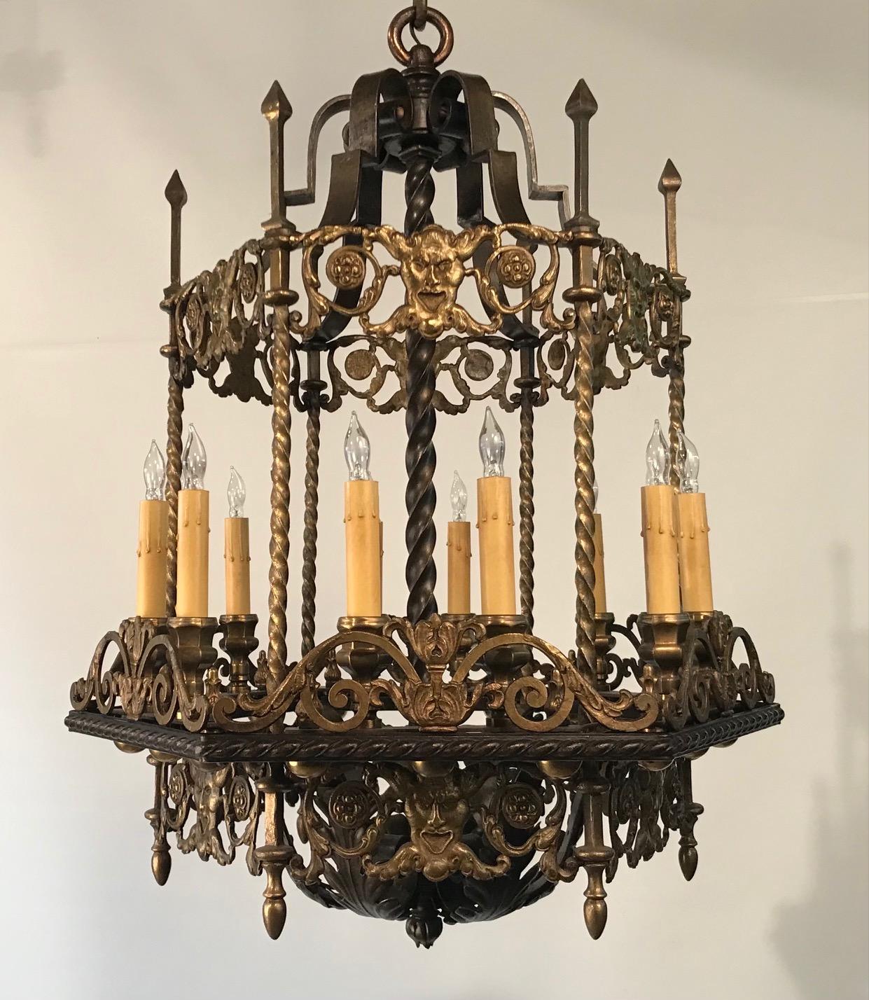 This unusual chandelier is made in this rather rare lantern form but without being enclosed in glazed panels. It is hexagonal, with two lights on each side. The upper section is enclosed by an openwork panel of scrolls and masks, a motif repeated on