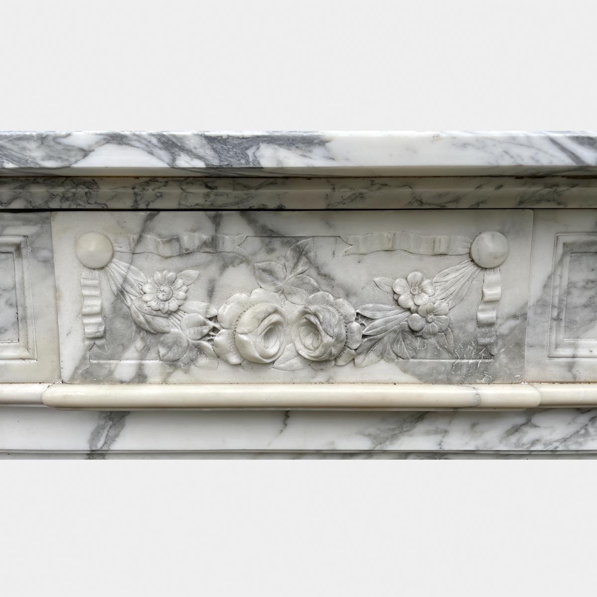 A Louis XVI style mid 19th century antique marble fireplace in richly variegated superior quality Arbescato marble. The jambs with stop flute panels with carved husks within. Square Patarae corner blocks flanking a fielded frieze with a carved