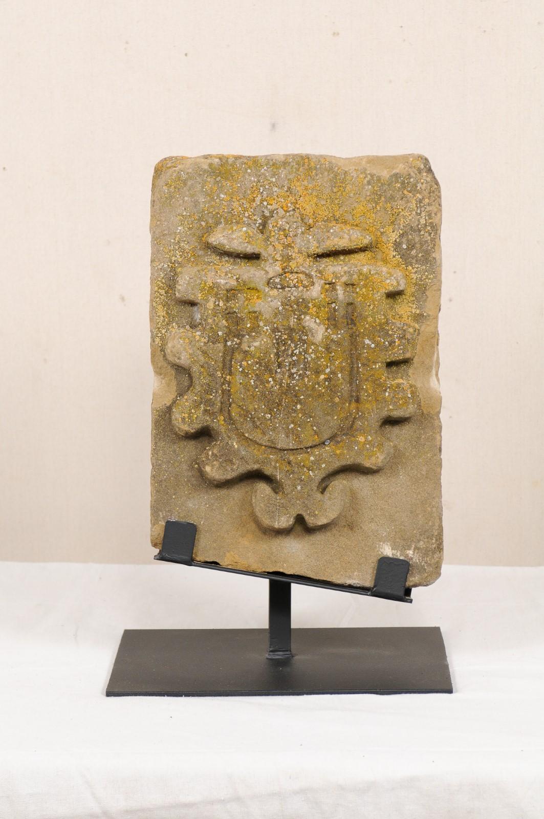 An 18th to 19th century carved stone architectural fragment from Aragon, Spain. This antique architectural fragment from Aragon has been hand-carved of stone, featuring a raised shield-shaped design with curvy outline about it's perimeter, and is